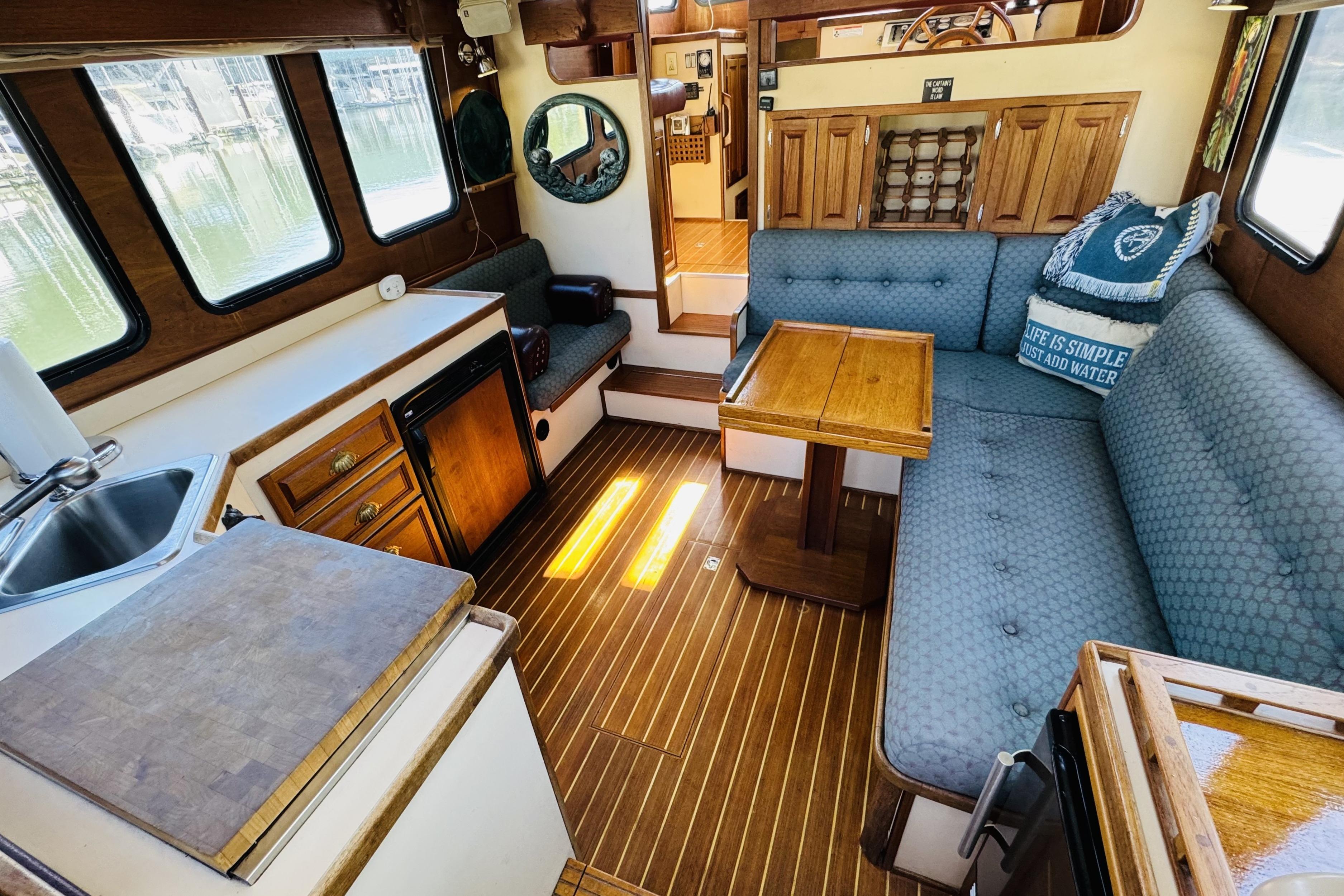 Interior of a 1996 Nordic Tug 32, featuring cozy seating and wooden cabinetry.