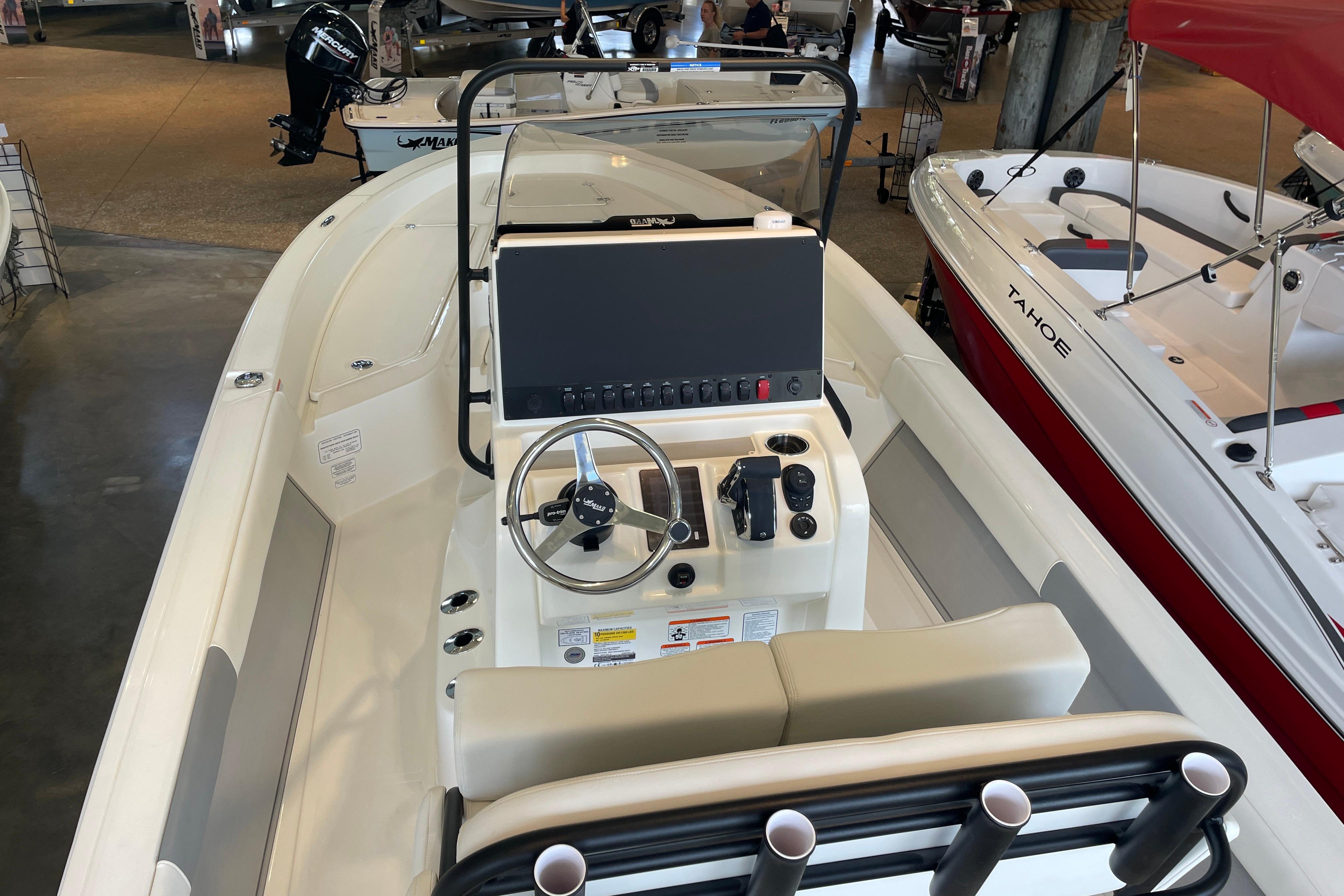 2026 Mako 24 APEX boat interior with steering console and seating in showroom.