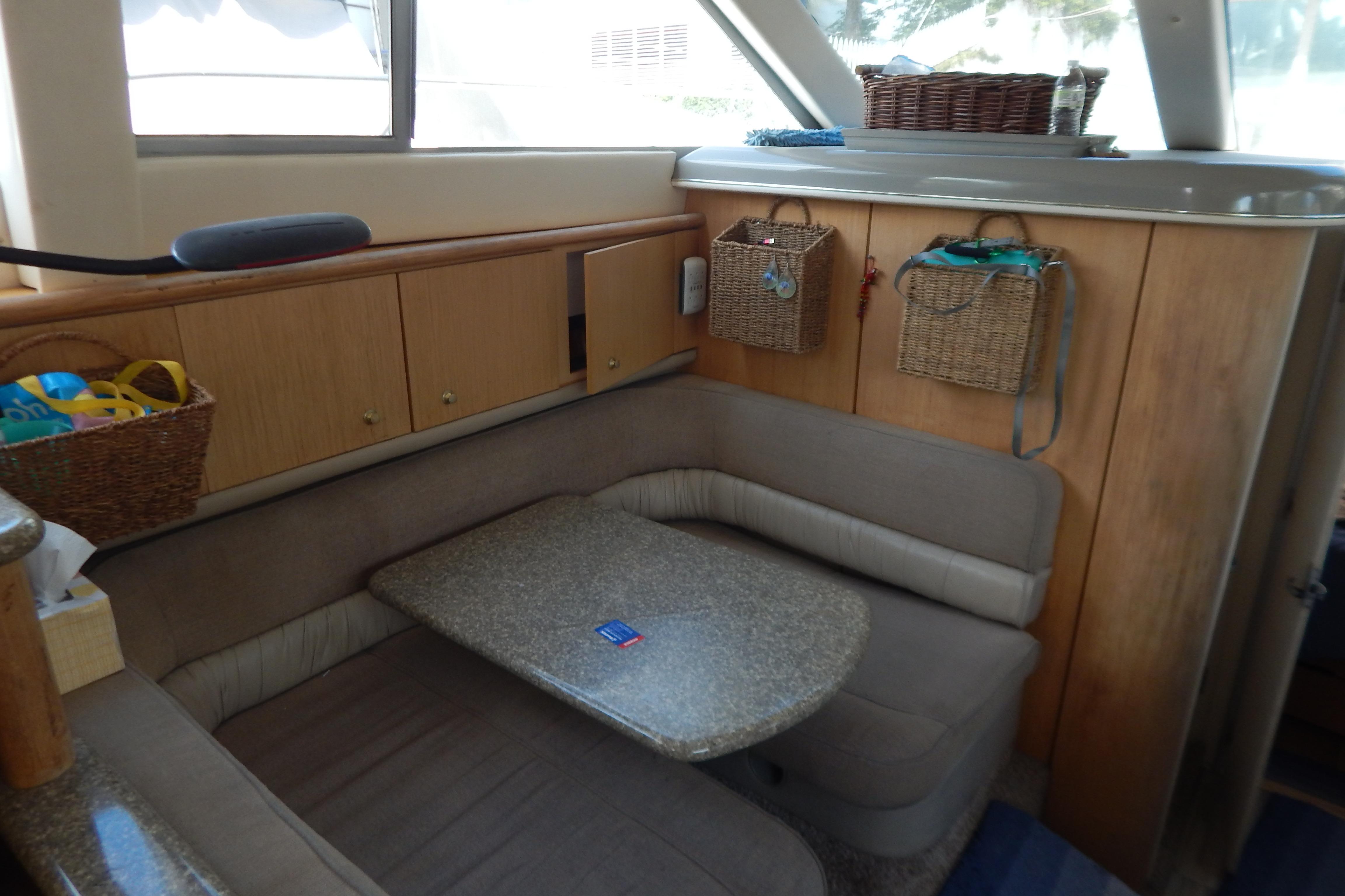 Cozy interior of 1998 Magnum 4100 SCR yacht with cushioned seating and wooden cabinetry.