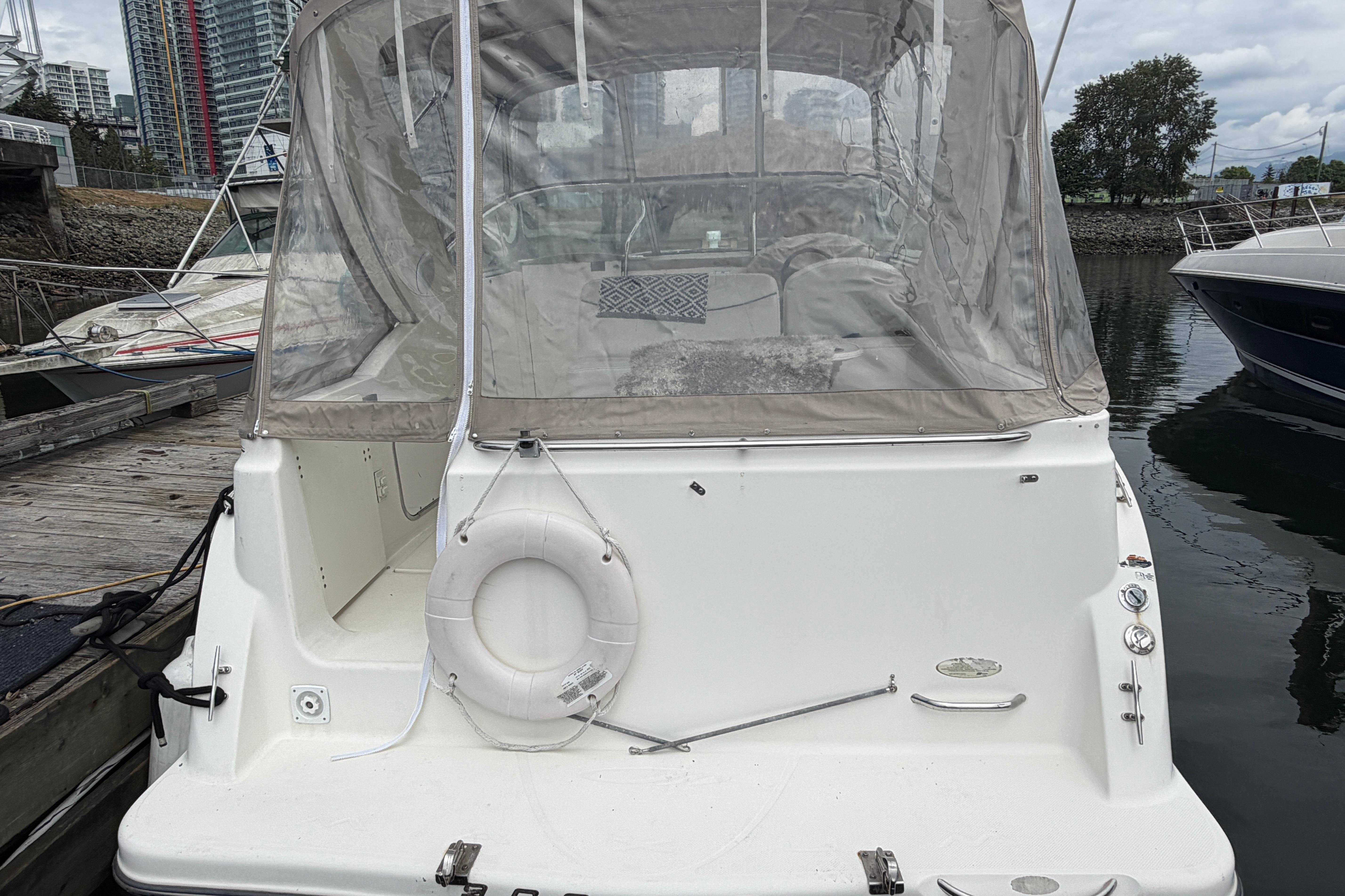 2003 Maxum 2900 SCR boat docked, featuring a covered cockpit and life preserver.