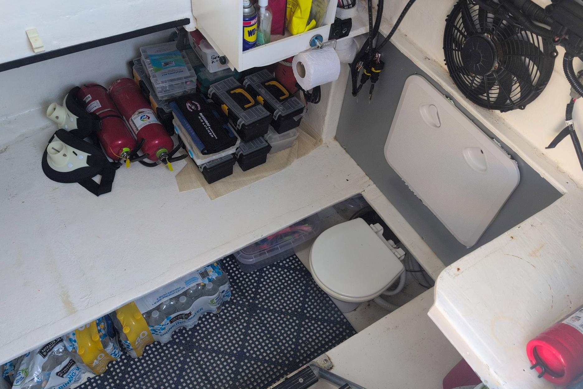 Storage area in a 1995 Ocean Master 34 boat with tools, fire extinguishers, and a toilet.