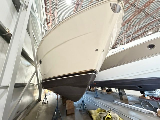 A 2005 Carver 44 Cockpit Motor Yacht is supported on stands in a warehouse.