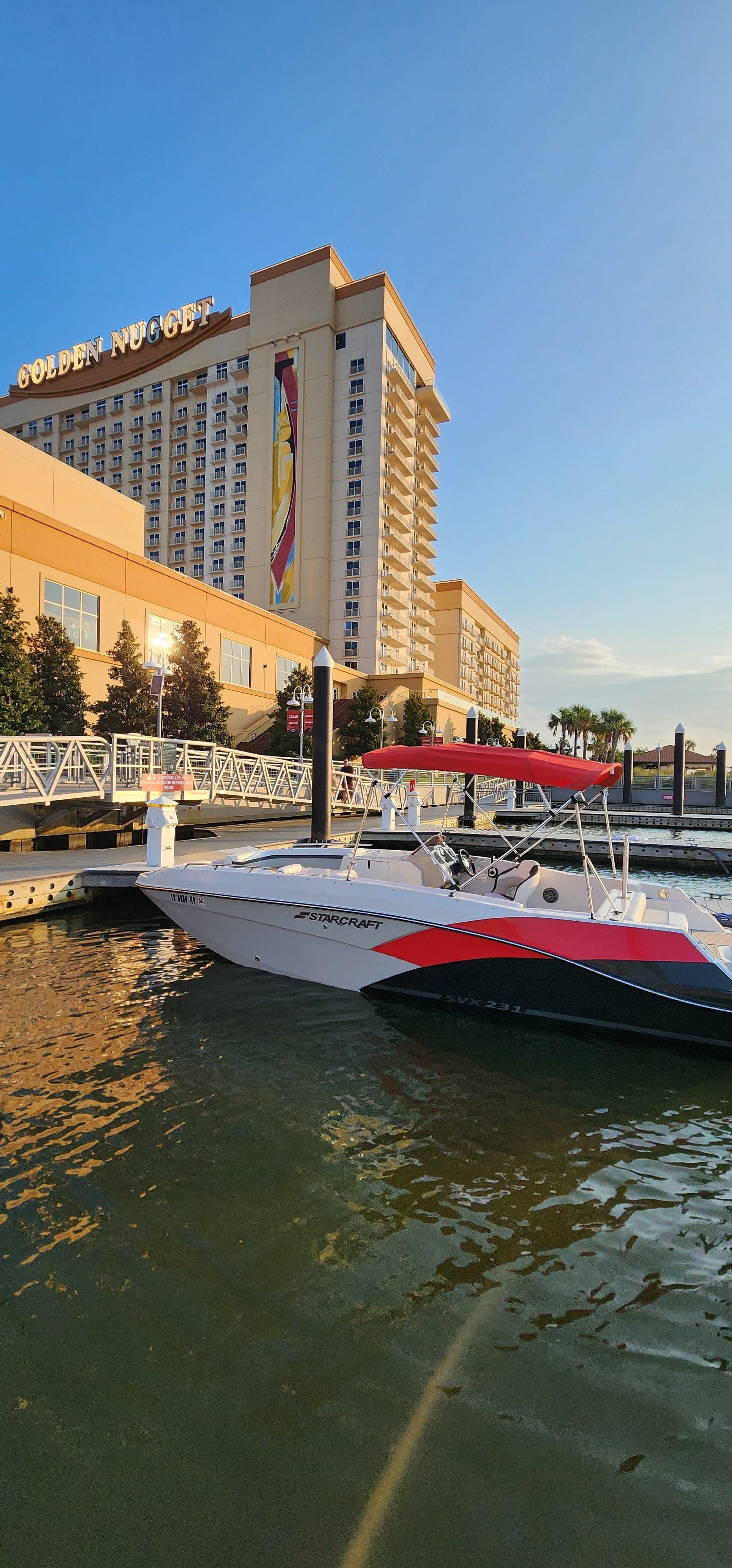A Starcraft boat is docked in the water near a large building named Golden Nugget.