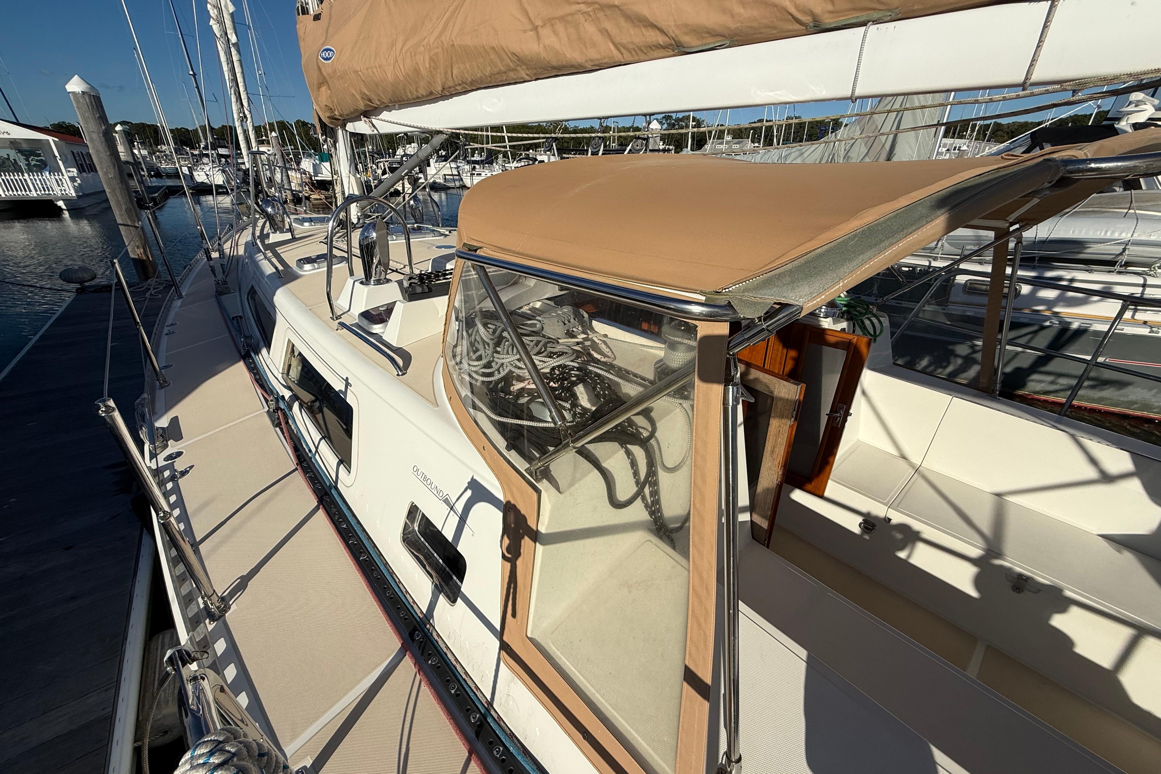 Sailboat docked at marina, Outbound 46 model, 2012, with tan canopy and clean deck.