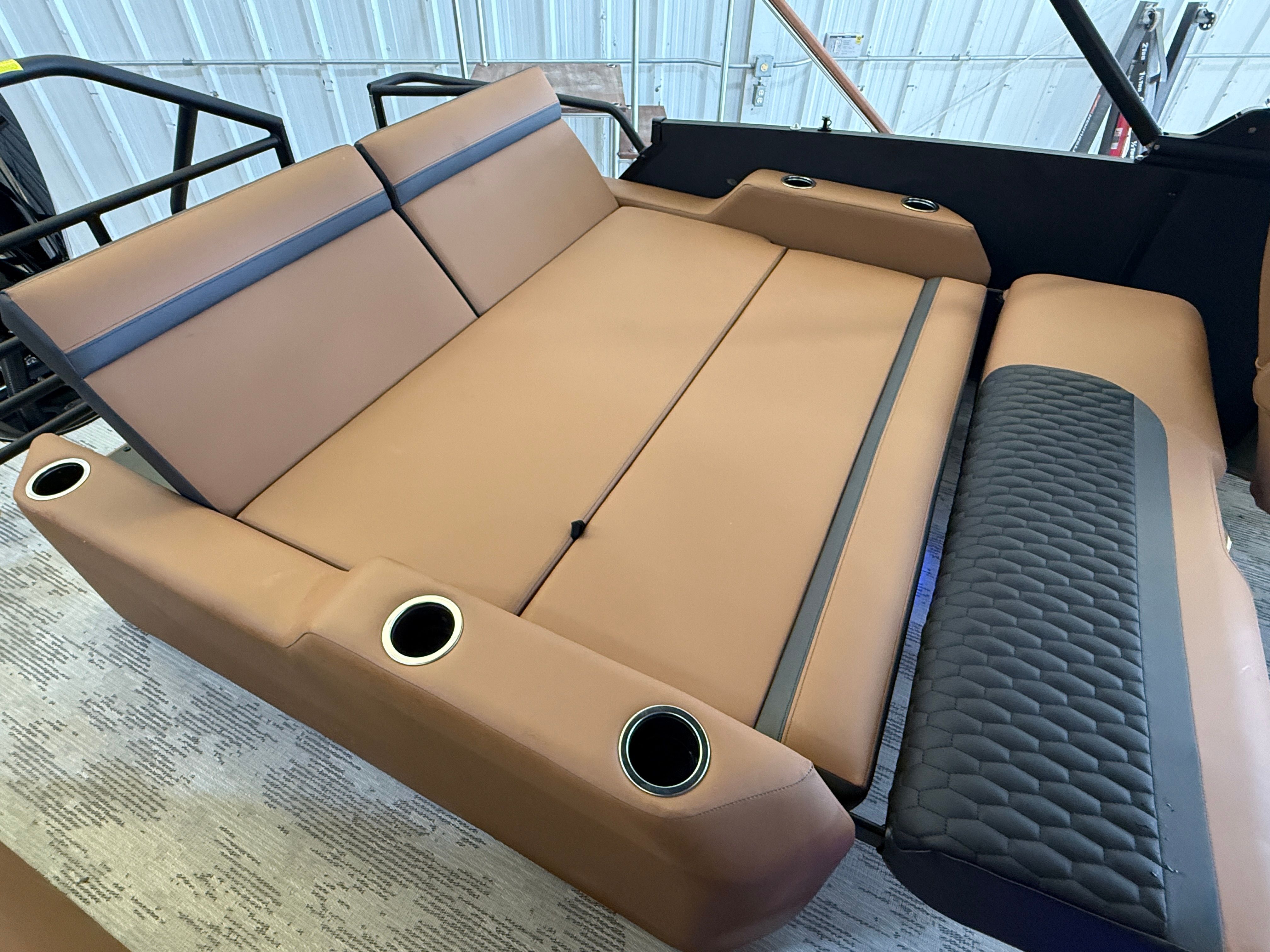 The image shows a luxurious lounging area with brown upholstery and cup holders.