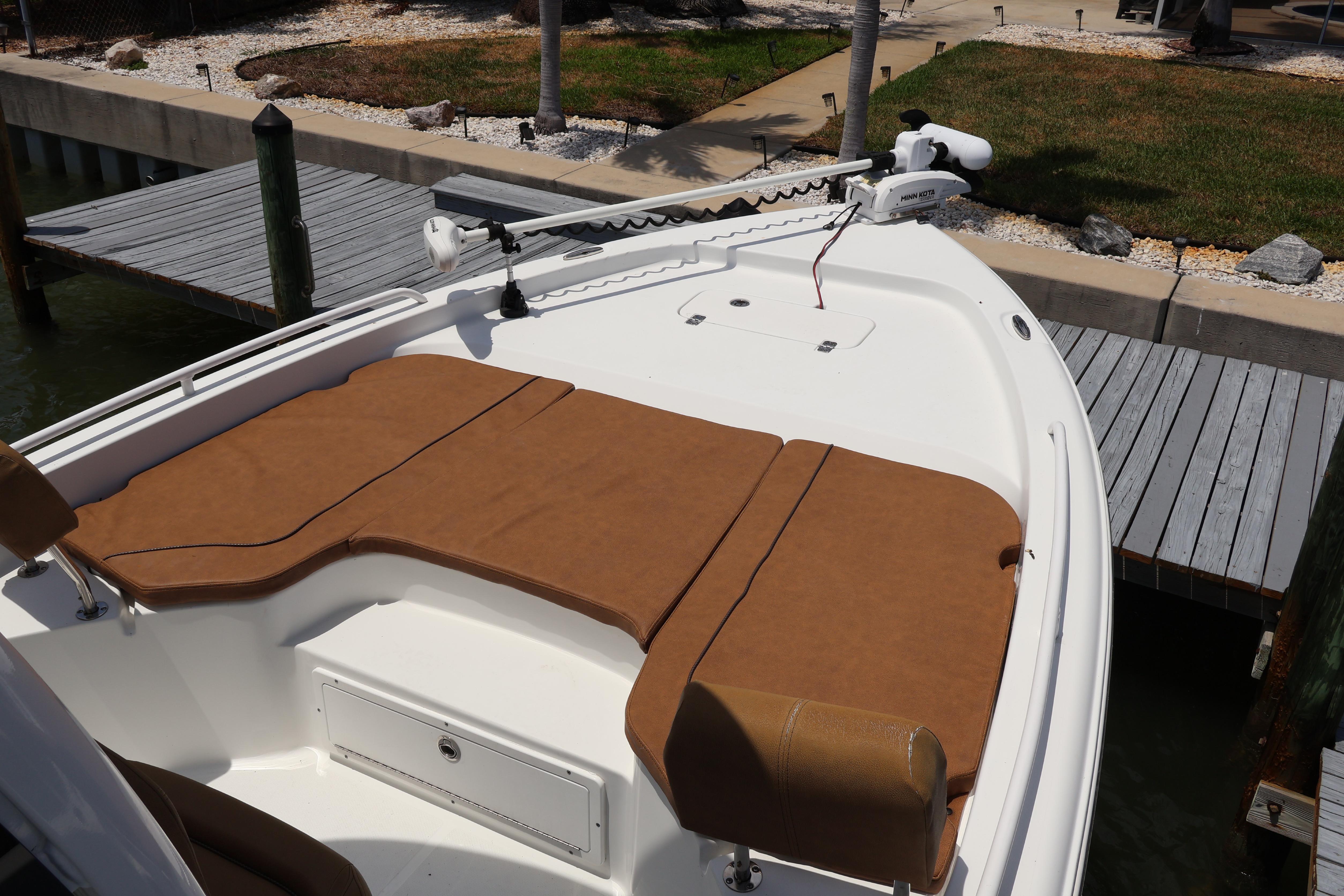 2022 Sea Hunt BX 25 FS boat with brown seating, docked near a wooden pier.