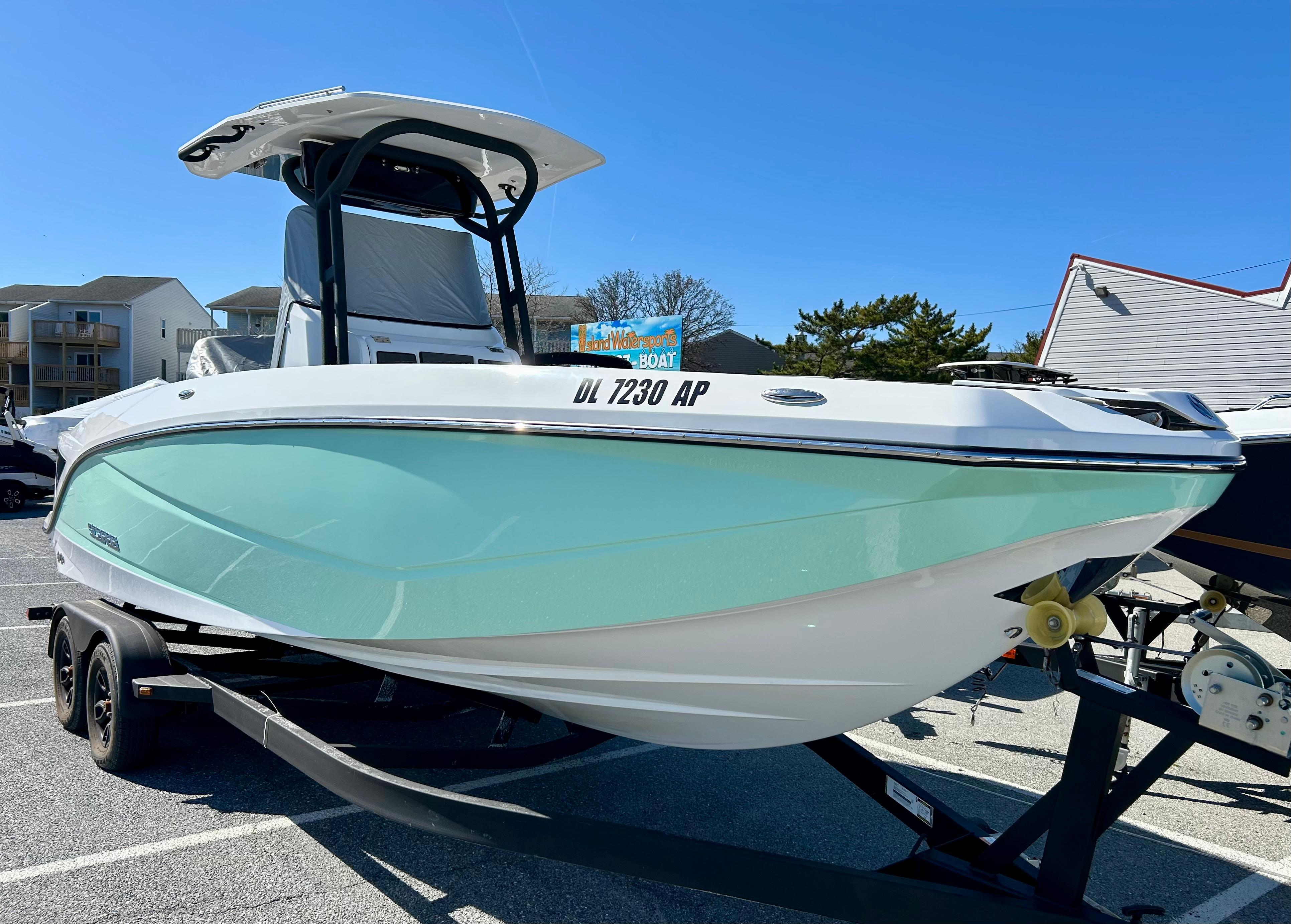 2024 Scarab 255 Open boat on trailer, mint green hull, parked outdoors.