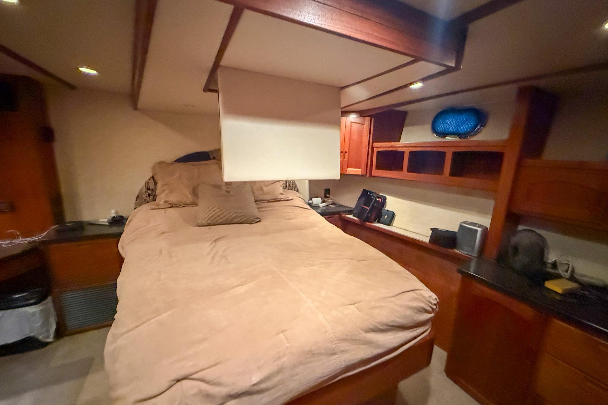 Cozy cabin interior of 2007 Nordic Tug 54 with bed and wooden storage.