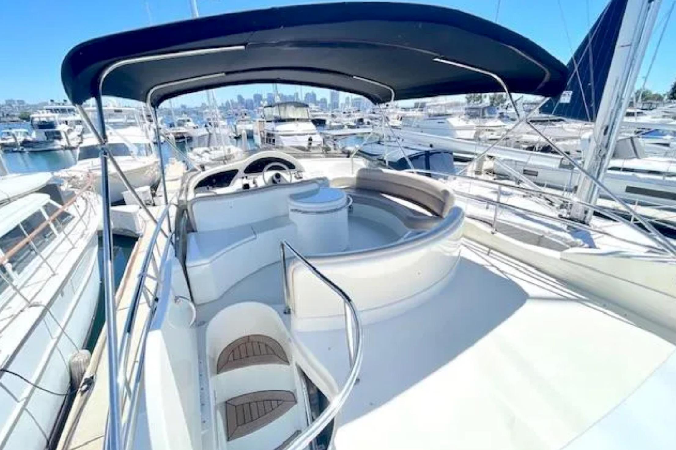 Flybridge of 2004 Azimut 46 yacht with seating, helm, and canopy in marina setting.