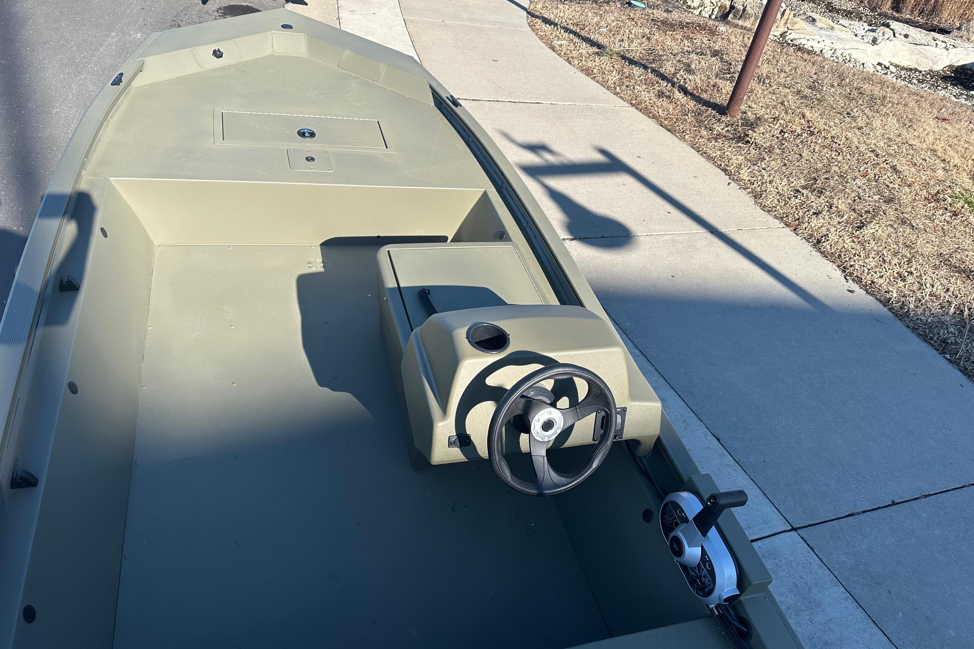2026 Tracker Grizzly 1648 SC boat interior with steering console, parked on a sunny street.