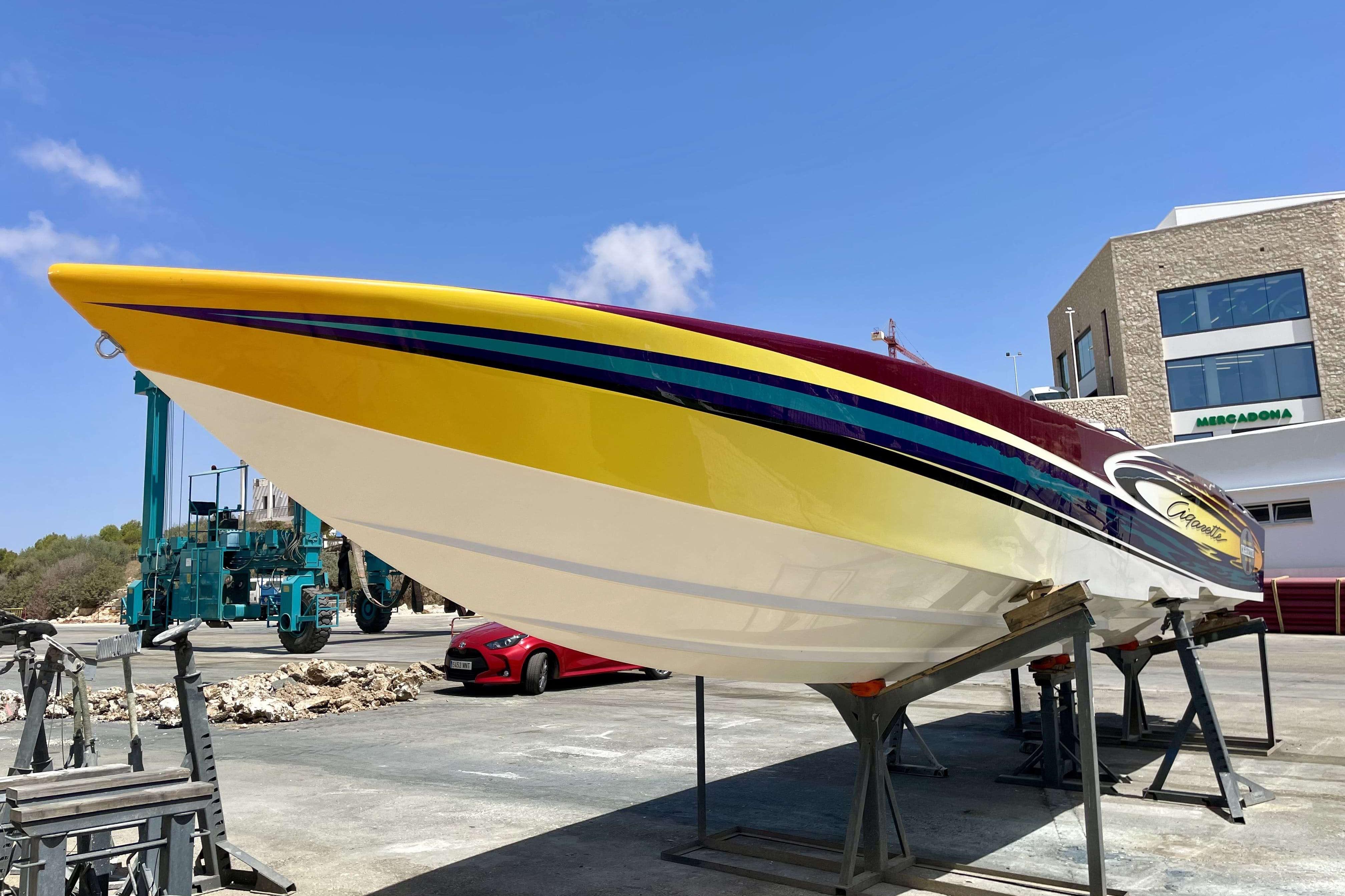 2004 Cigarette 36' Gladiator boat on stands, vibrant yellow and maroon design.