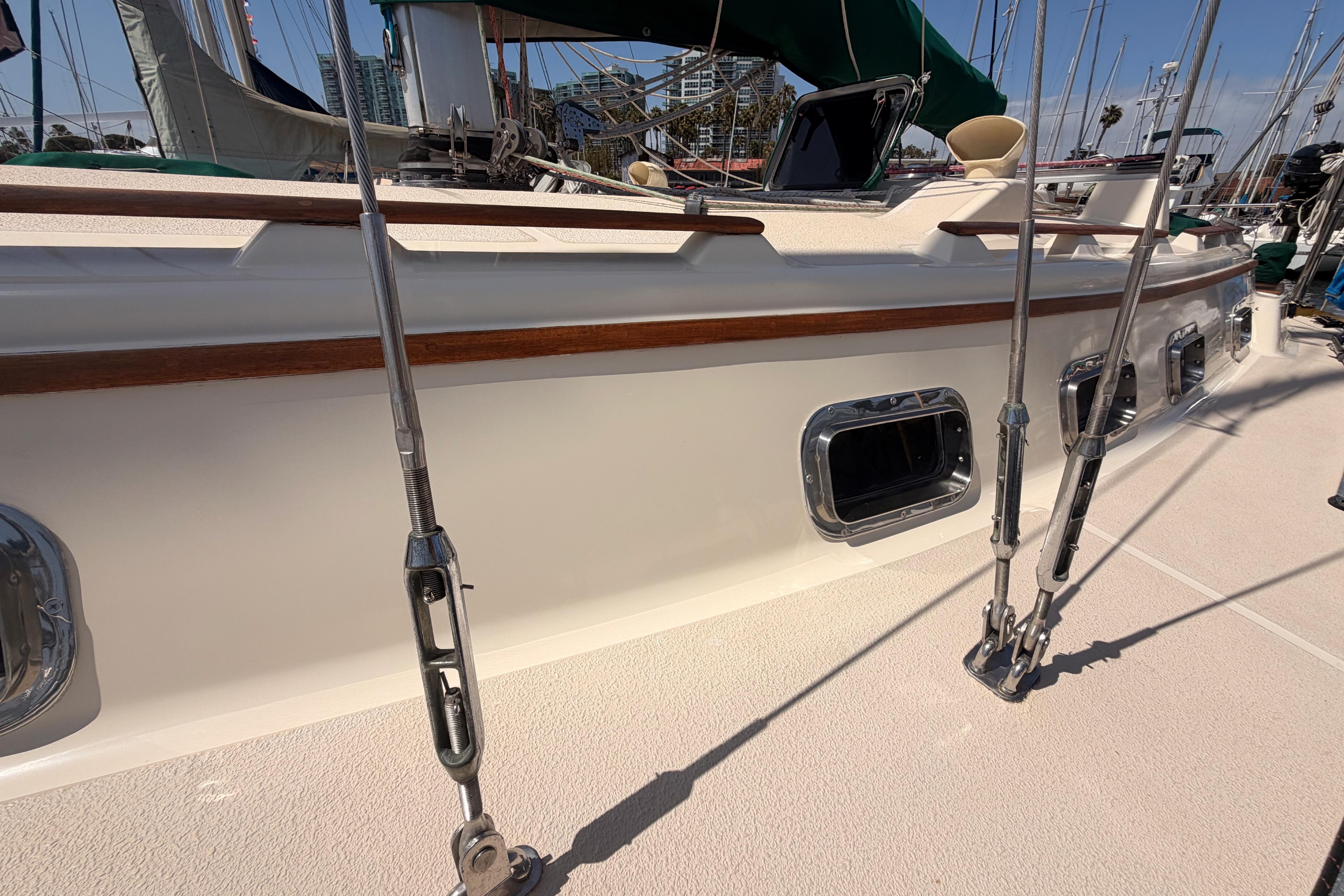 Sailboat deck of 1991 Caliber 33, featuring rigging and portholes in a marina setting.