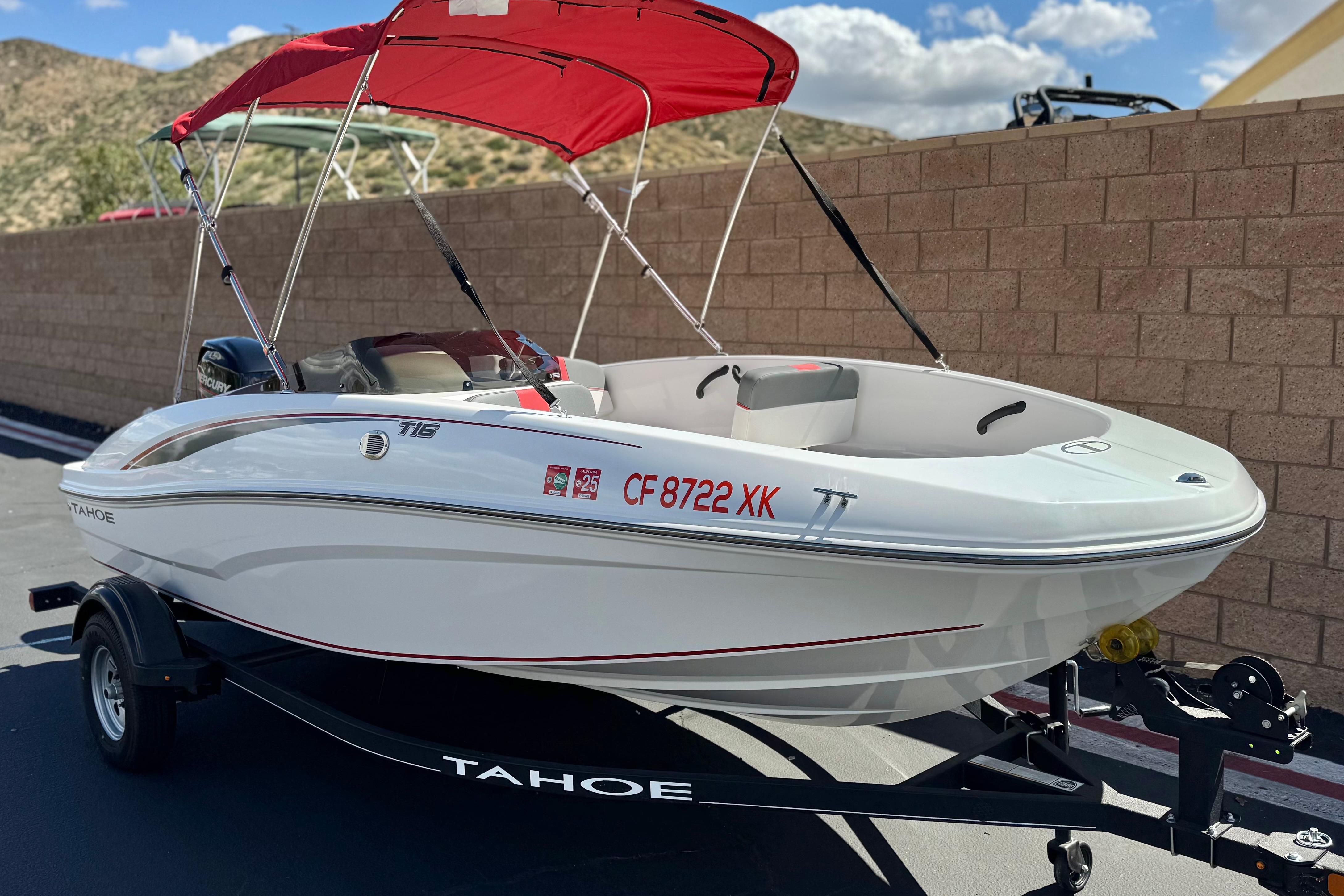 2024 Tahoe T16 boat with red canopy on trailer, parked outdoors.