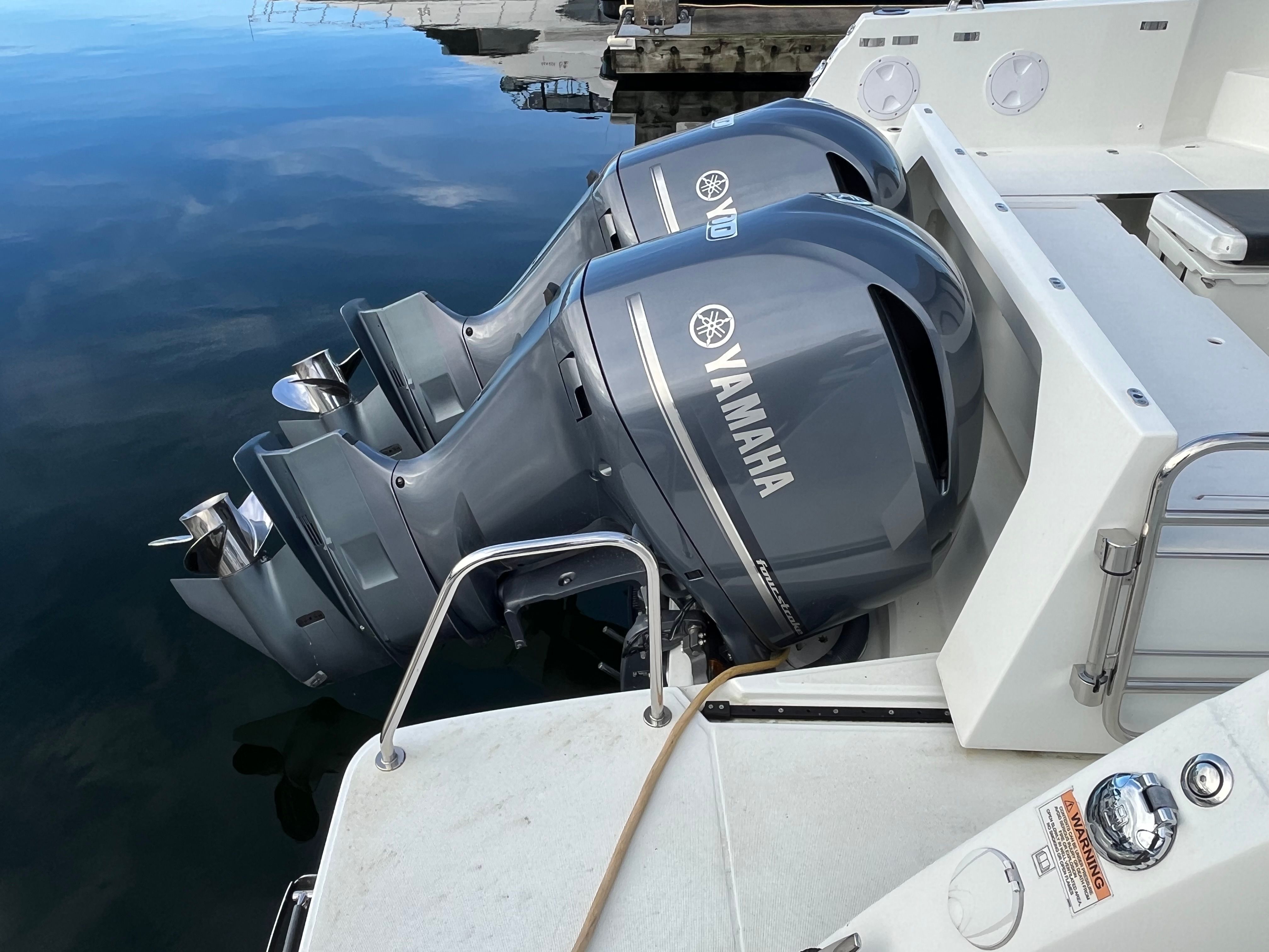 Two Yamaha outboard engines on a Jeanneau NC 1095 boat, floating on calm water.