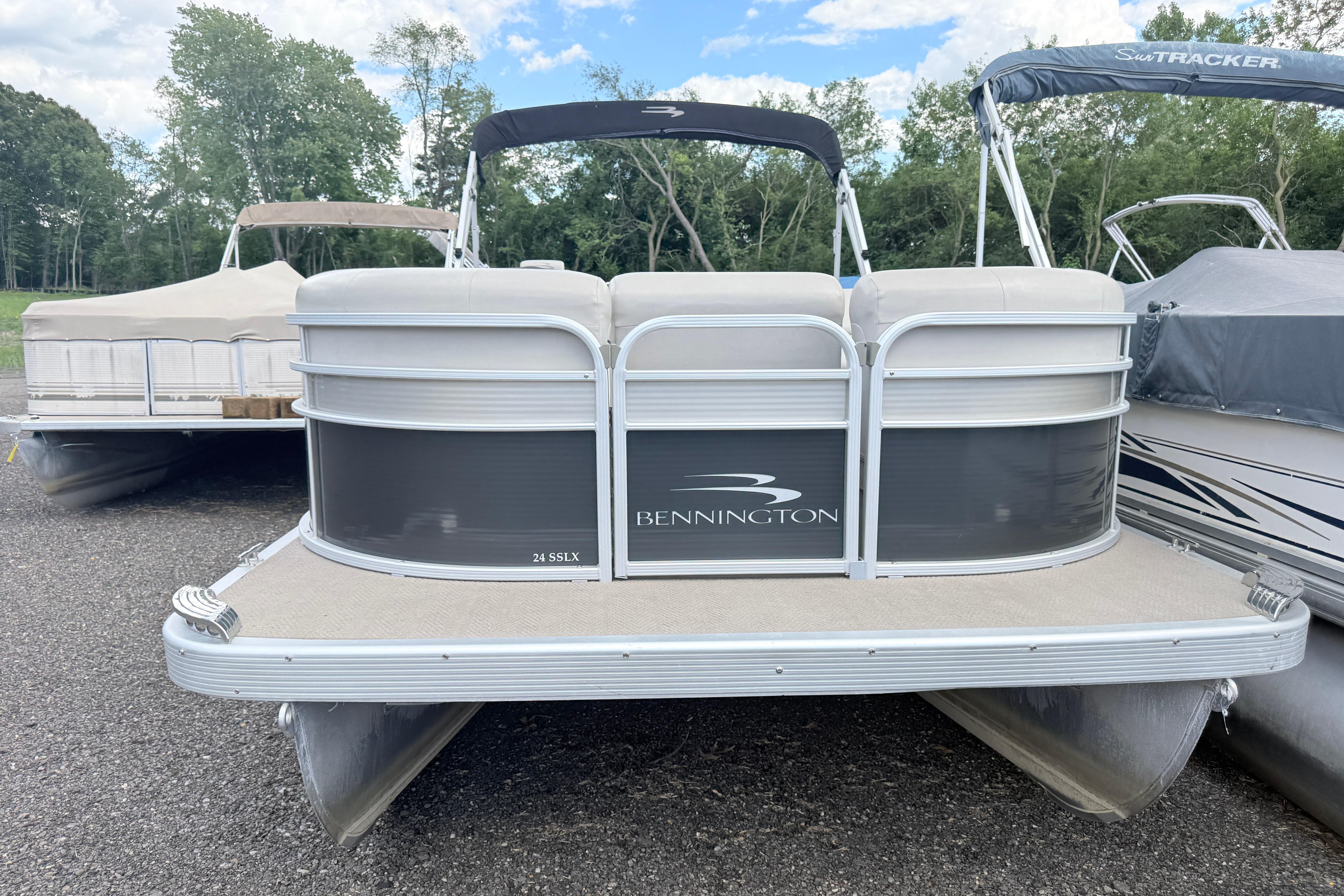 2015 Bennington 24SSLX pontoon boat parked on gravel with trees in background.