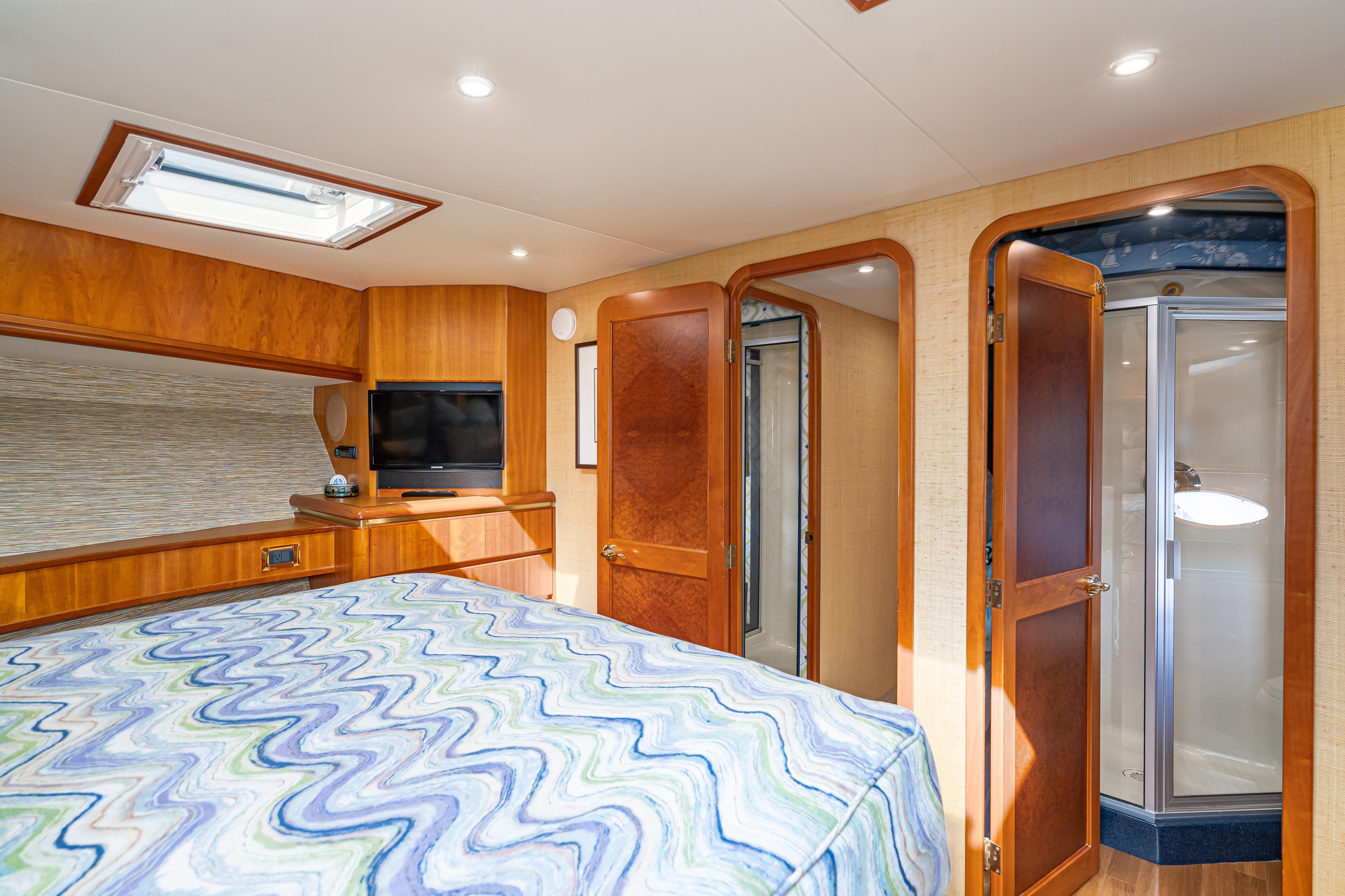 Luxurious 2001 West Bay Sonship yacht bedroom with wood accents and ensuite bathroom.