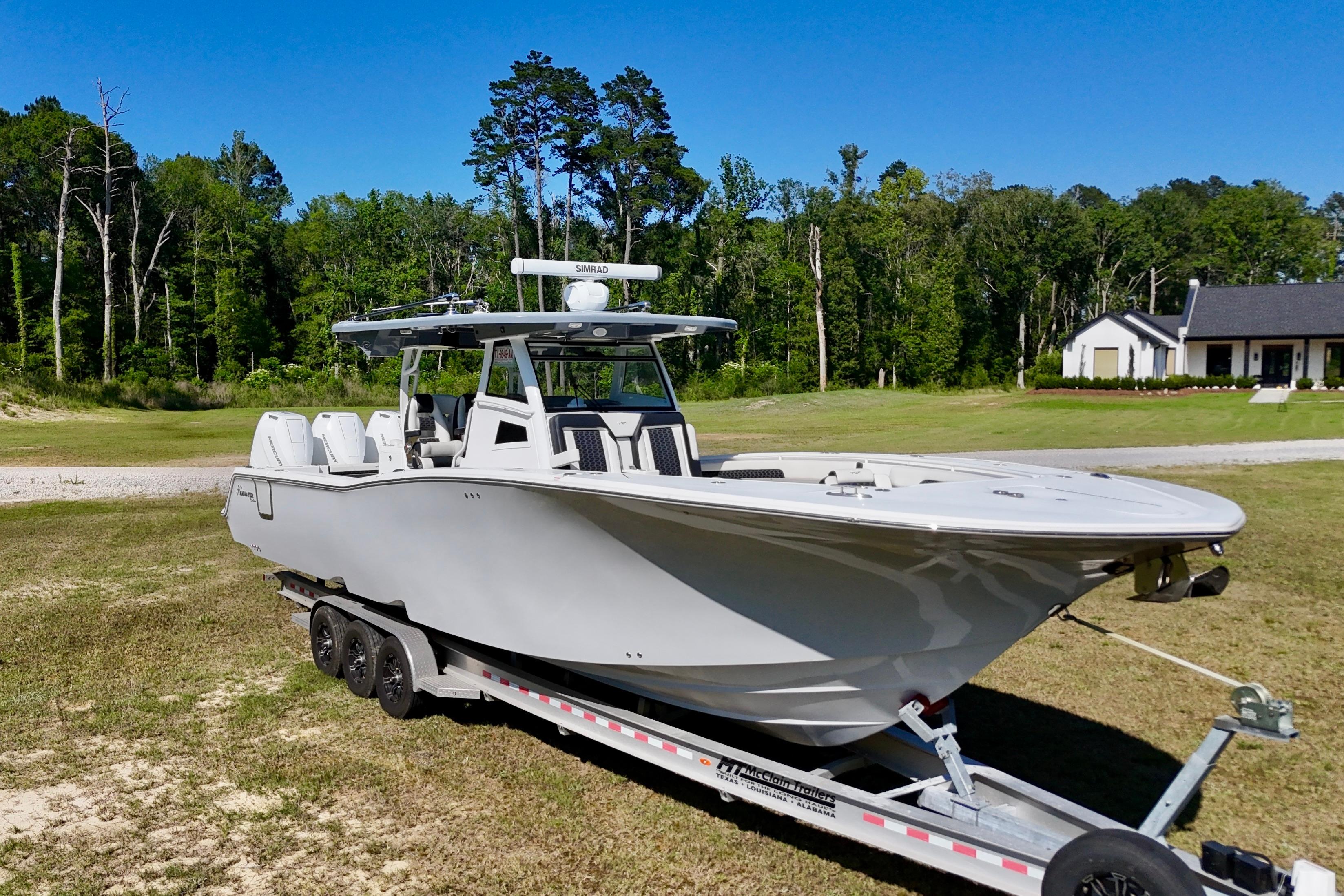 2024 Tidewater 380 CC Adventure boat on trailer, set against a lush green landscape.