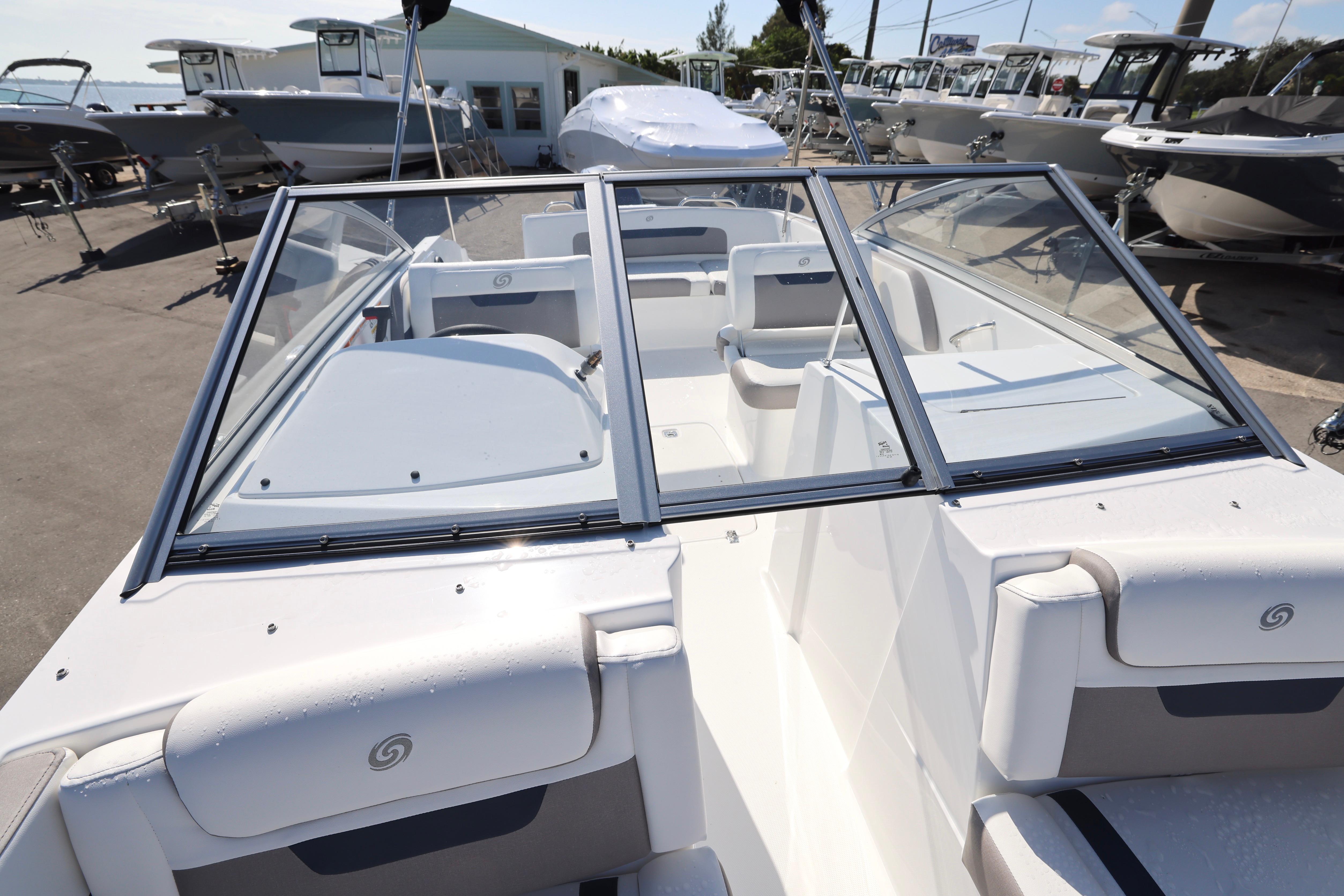 2026 Hurricane SunDeck 235 OB boat interior with seating and windshield, displayed outdoors.