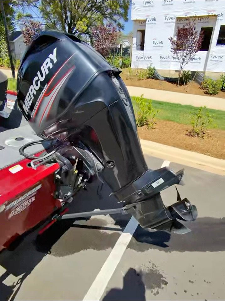 A Mercury outboard motor on a red boat, parked in a parking lot.