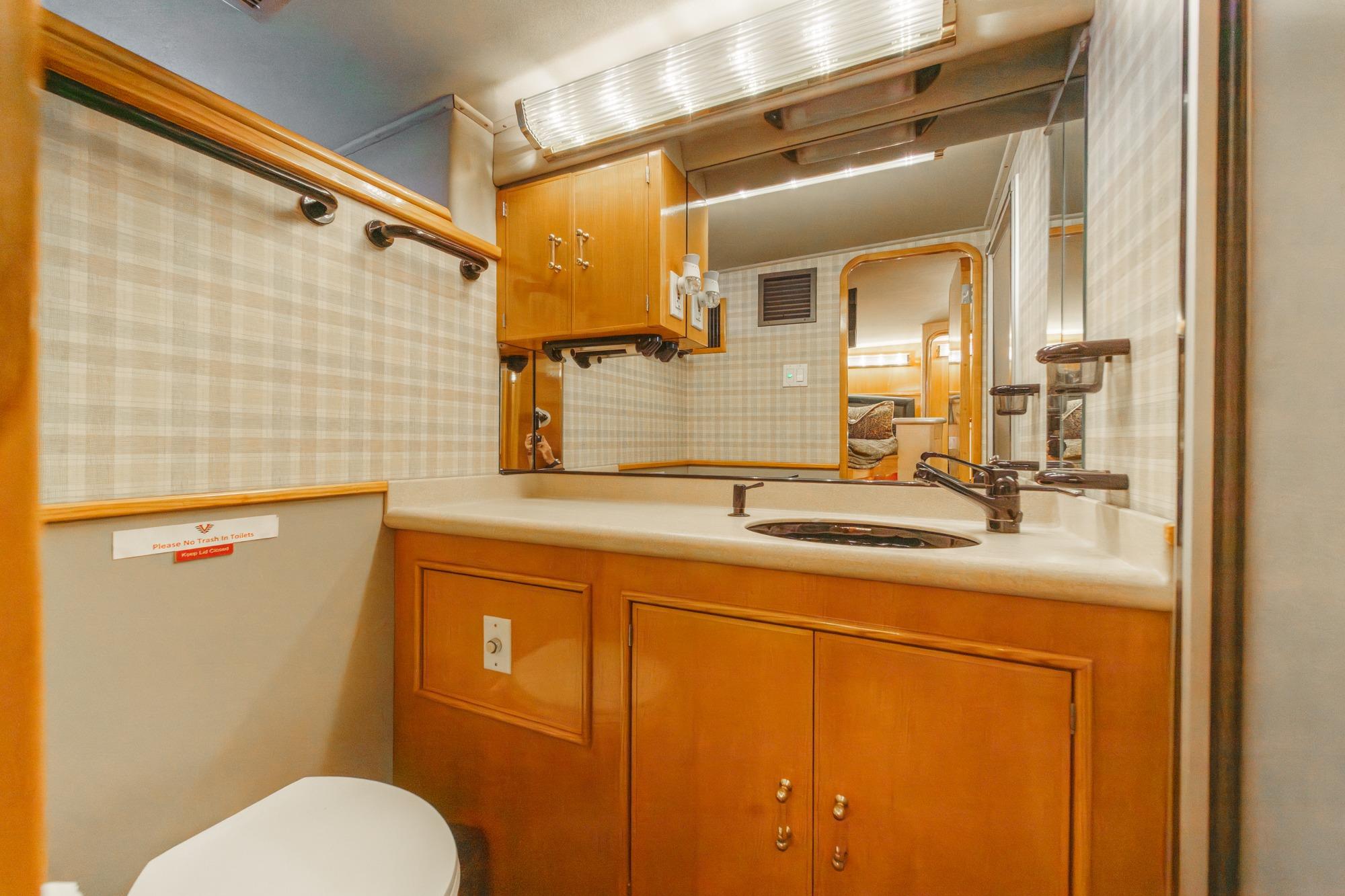 Bathroom interior of a 1990 Seaton Long Range Cruiser with wood cabinetry and modern fixtures.