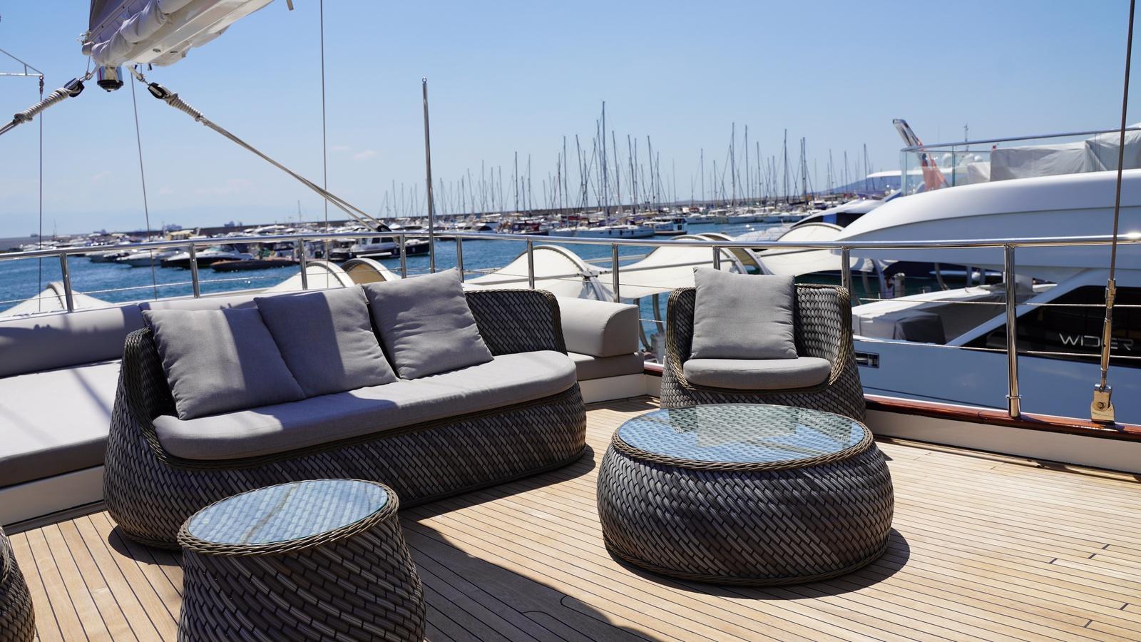 Luxurious yacht deck with modern seating, overlooking a marina filled with boats.