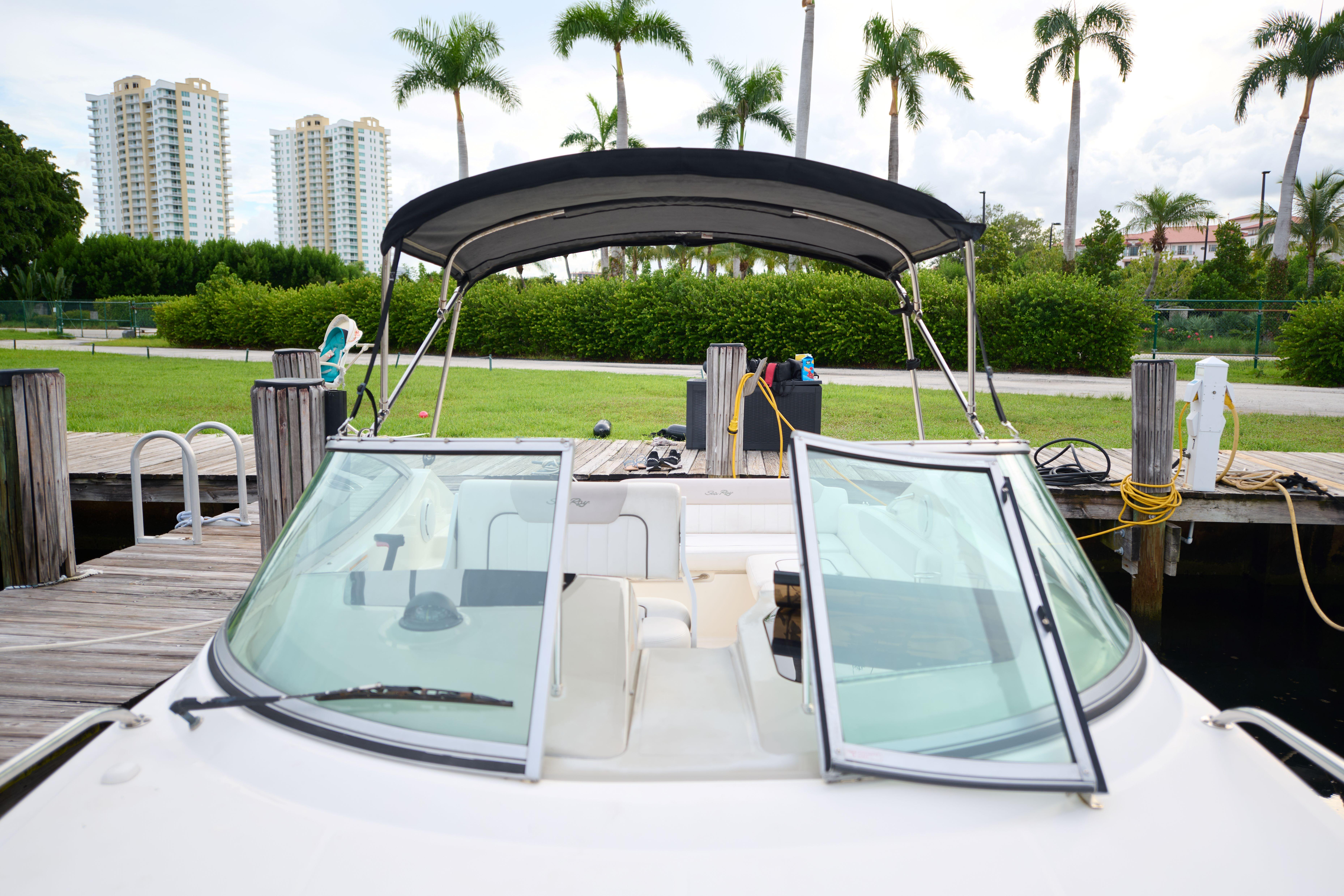 2011 Sea Ray 260 Sundancer docked, with open windshield and lush greenery in the background.