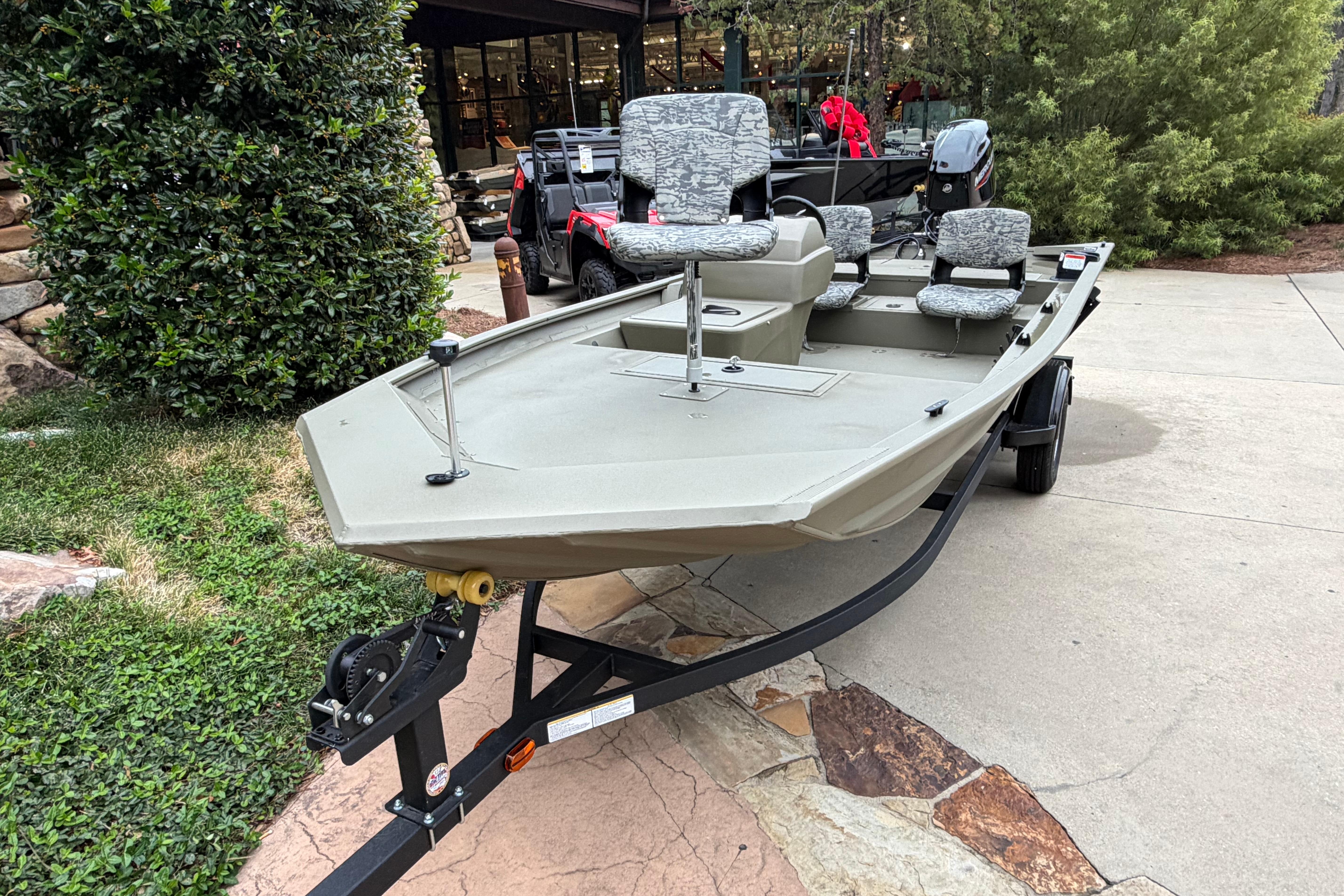 2026 Tracker Grizzly 1754 SC boat on trailer, parked outdoors near greenery.