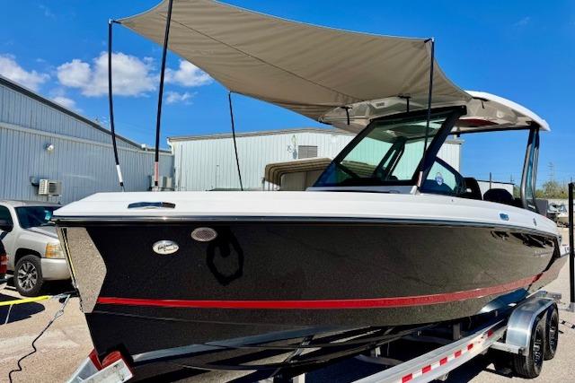 2026 Monterey Elite 25 OB boat with canopy on trailer, parked outdoors.