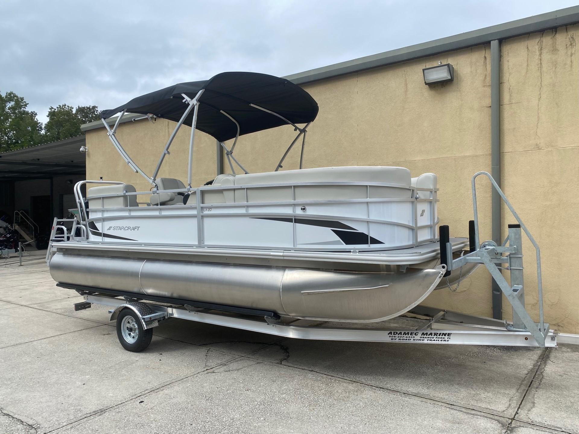 2024 Starcraft LX 20 R pontoon boat on trailer, parked outdoors.