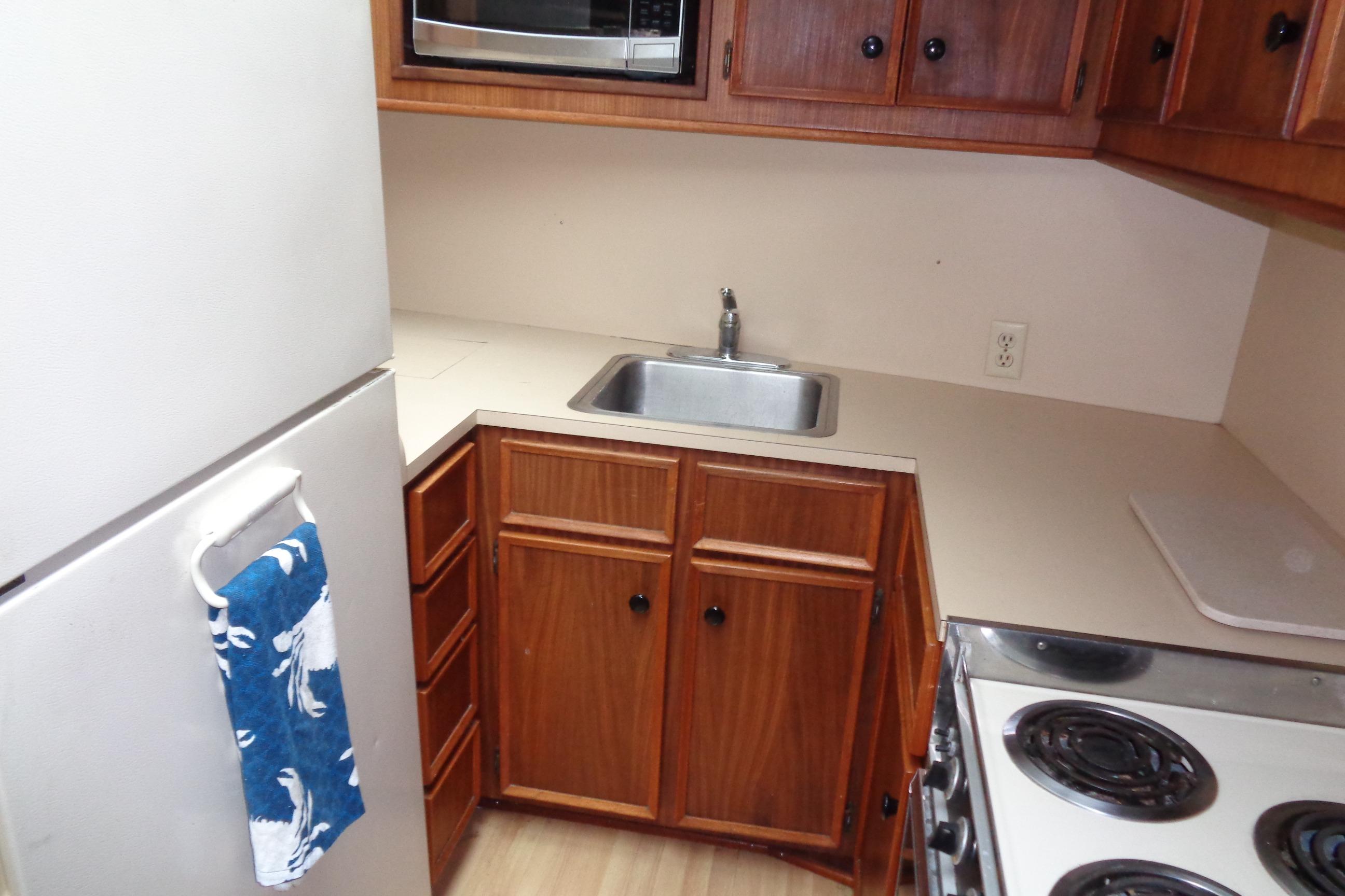 Compact kitchen in 1981 Hatteras 48 Cockpit Motor Yacht with wooden cabinets and appliances.