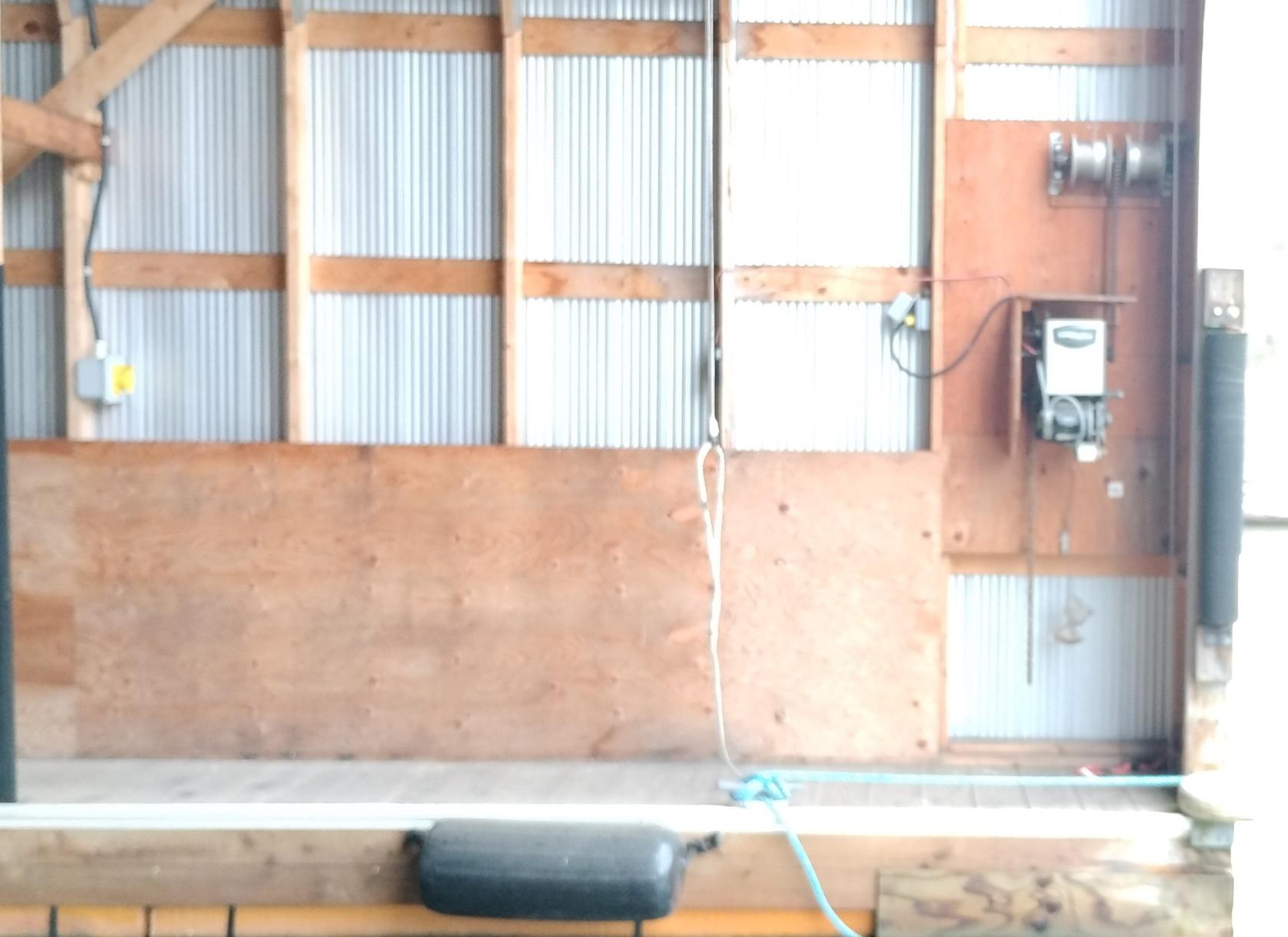 Custom 2012 boathouse interior with wooden and metal paneling, electrical equipment, and dock bumper.