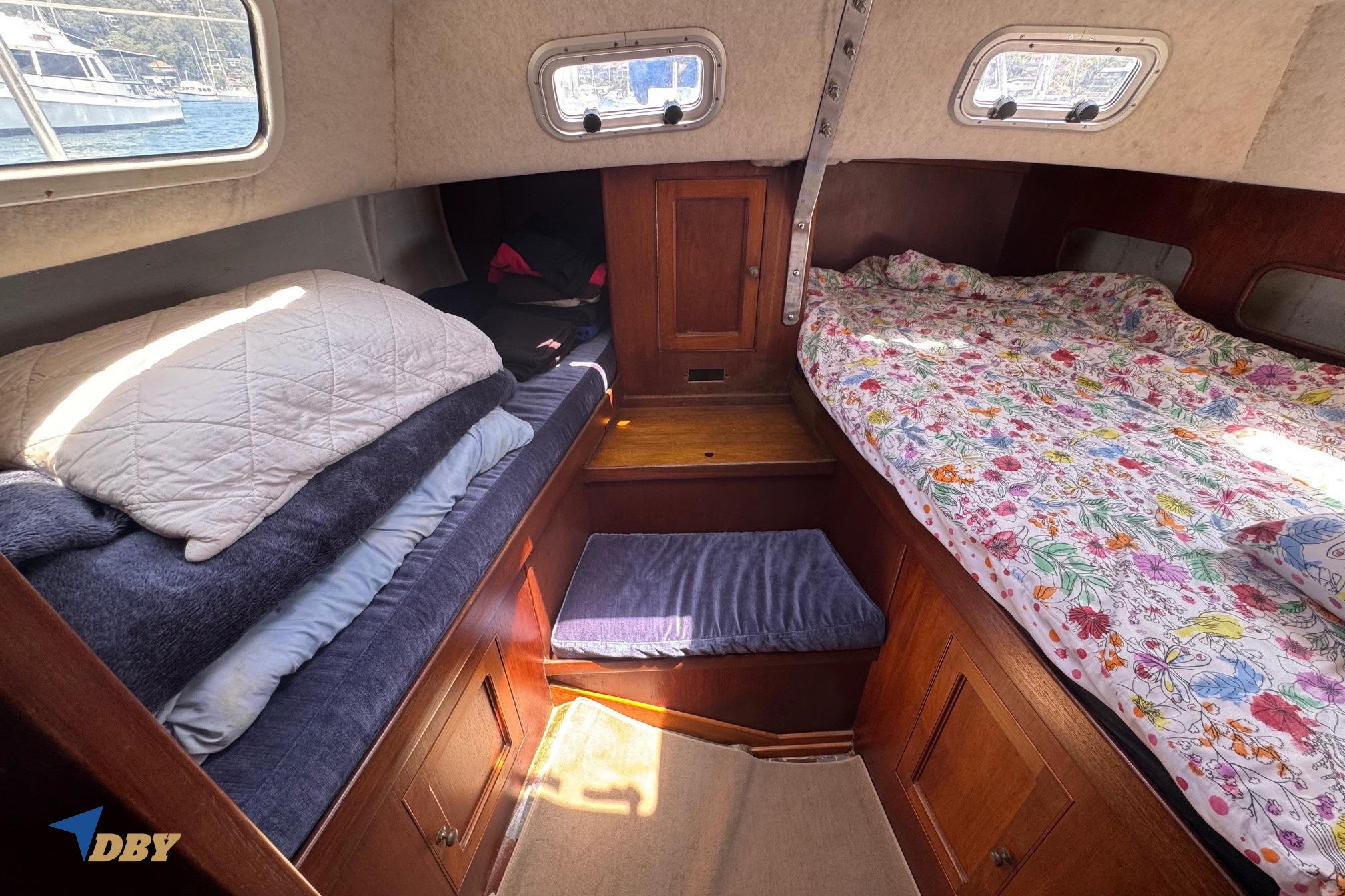 Cozy cabin interior of 1987 Bowman 47 sailboat with beds and wooden storage.