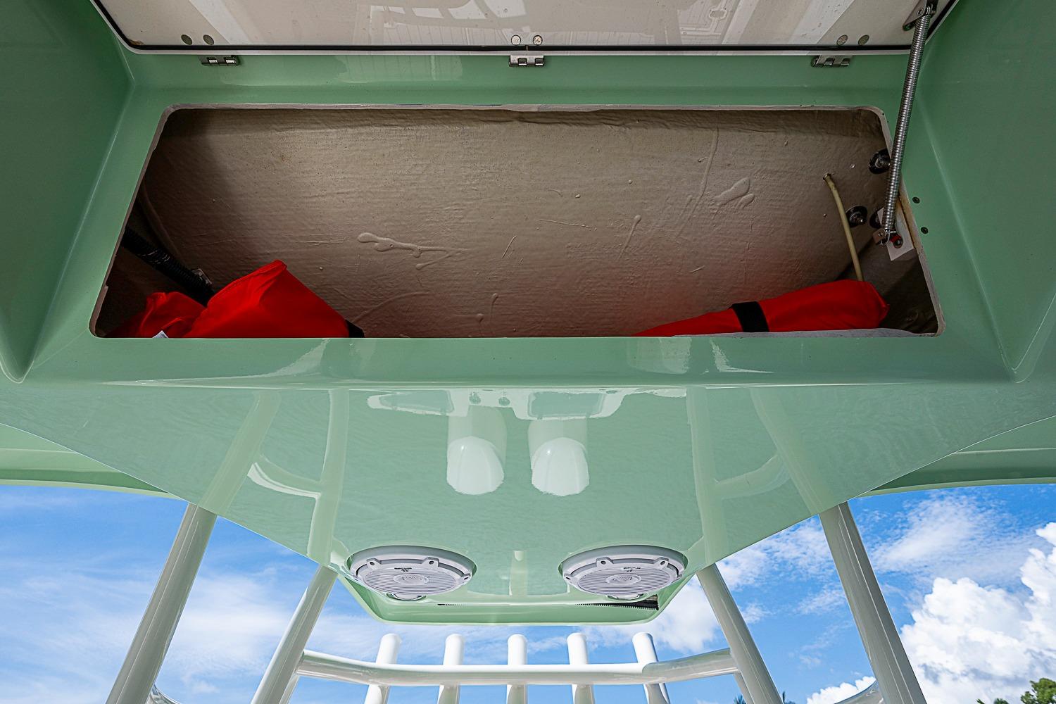 Storage compartment on 2019 Cobia 320 Center Console boat, featuring life jackets and clear sky background.