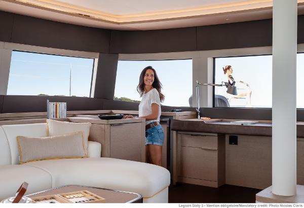 Woman in Lagoon SIXTY 5 yacht interior, 2025 model, enjoying luxurious modern design.