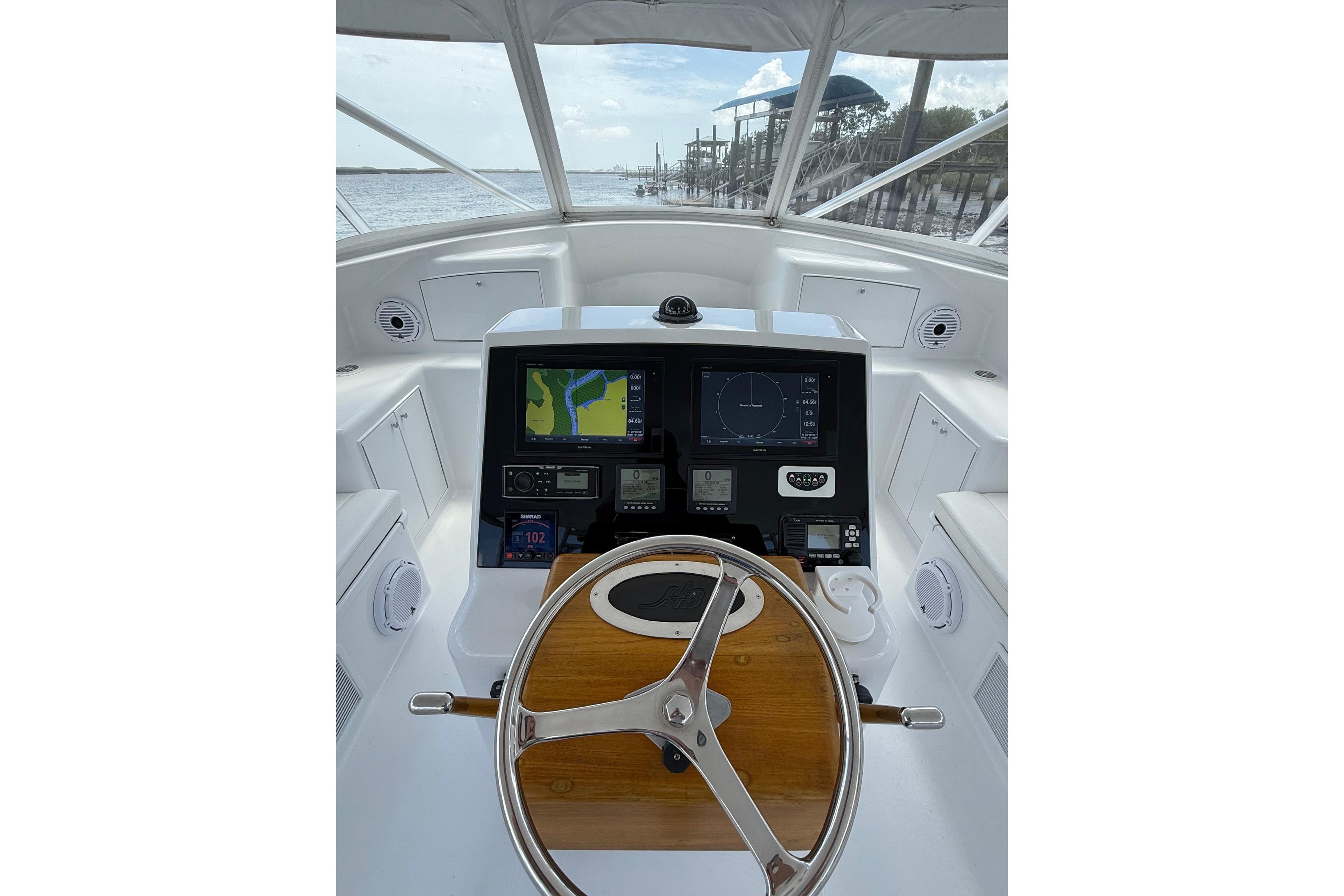 Helm of 2006 Custom Carolina Heritage Express boat with navigation screens and wooden steering wheel.