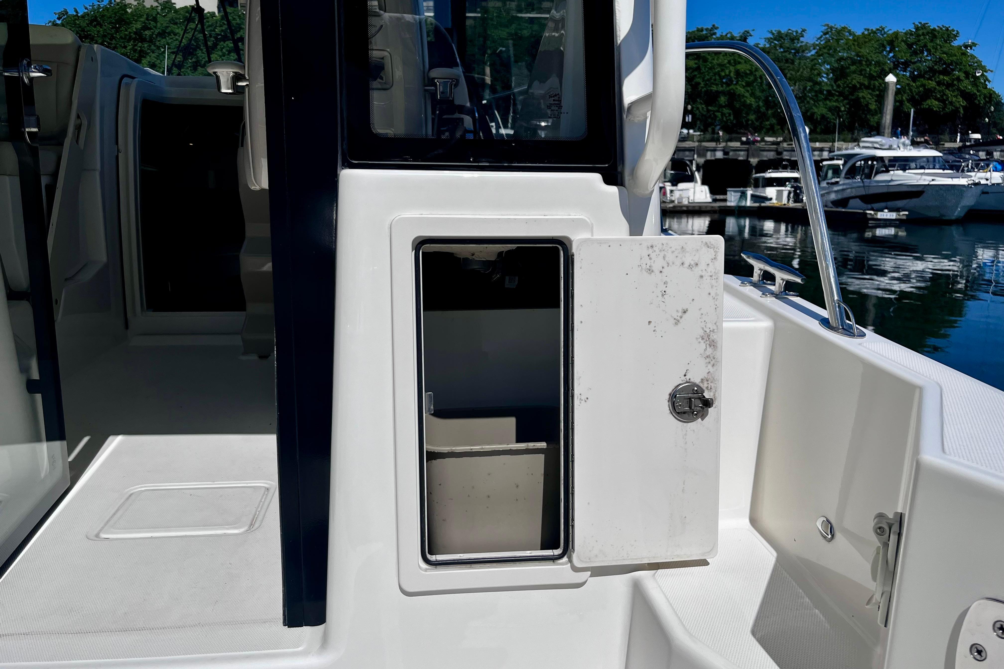 2026 Boston Whaler 325 Conquest Pilothouse interior with open storage compartment, docked at marina.