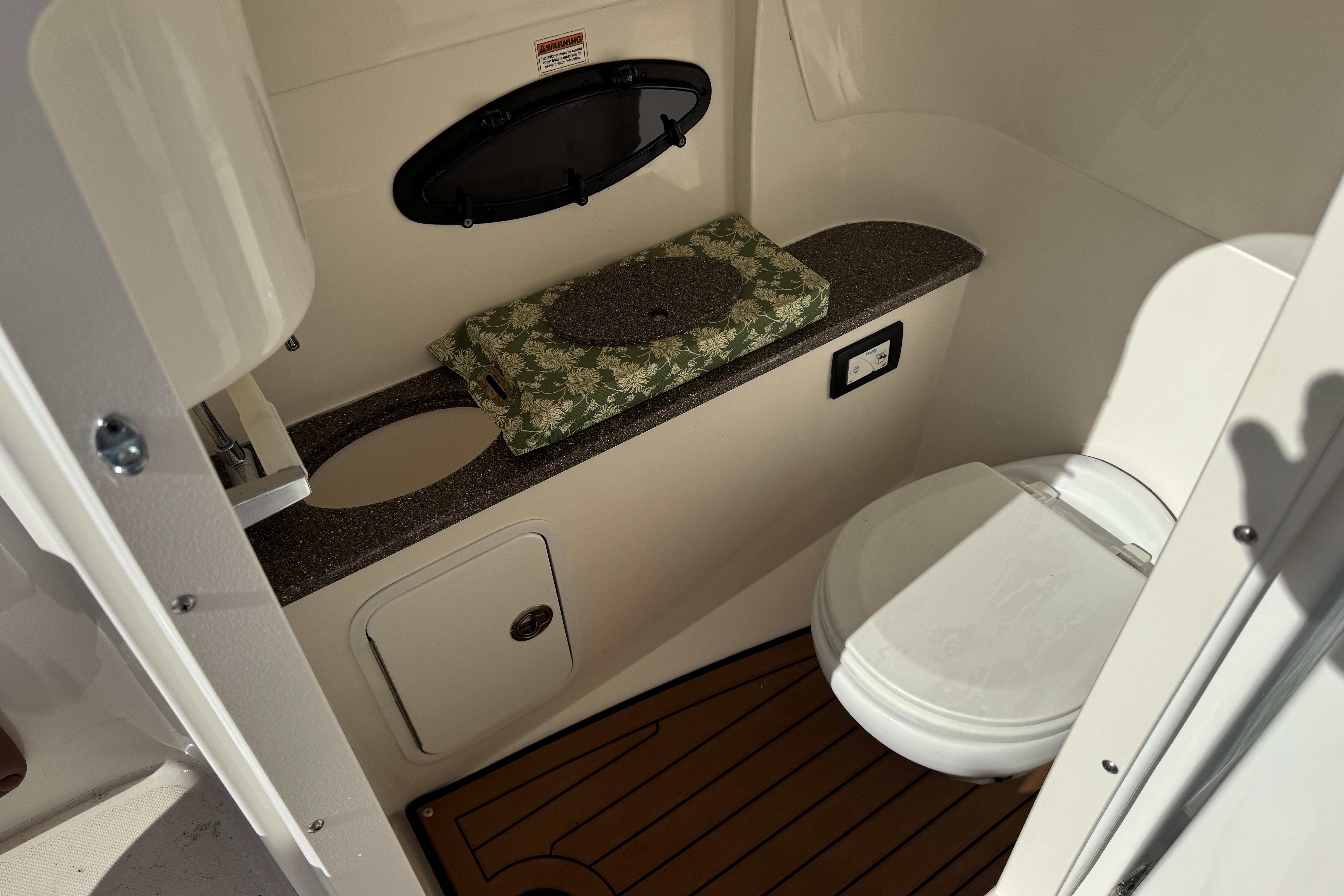 2018 Hurricane SunDeck 2400 OB boat bathroom with toilet and countertop.