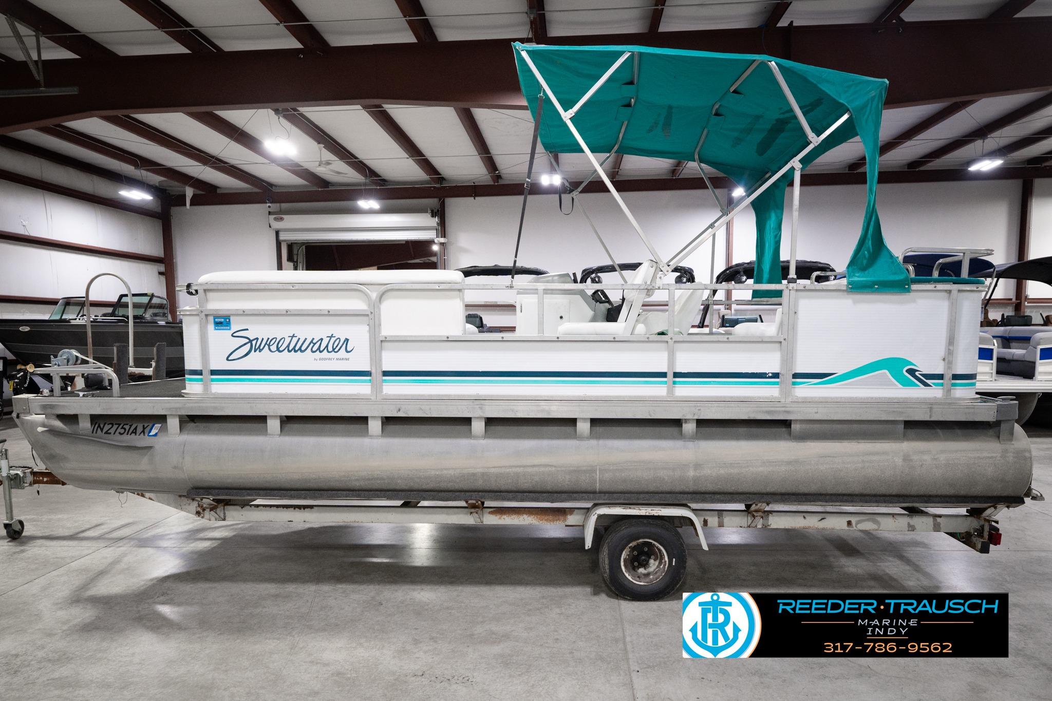 1992 Godfrey Sweetwater pontoon boat with teal canopy in indoor showroom.