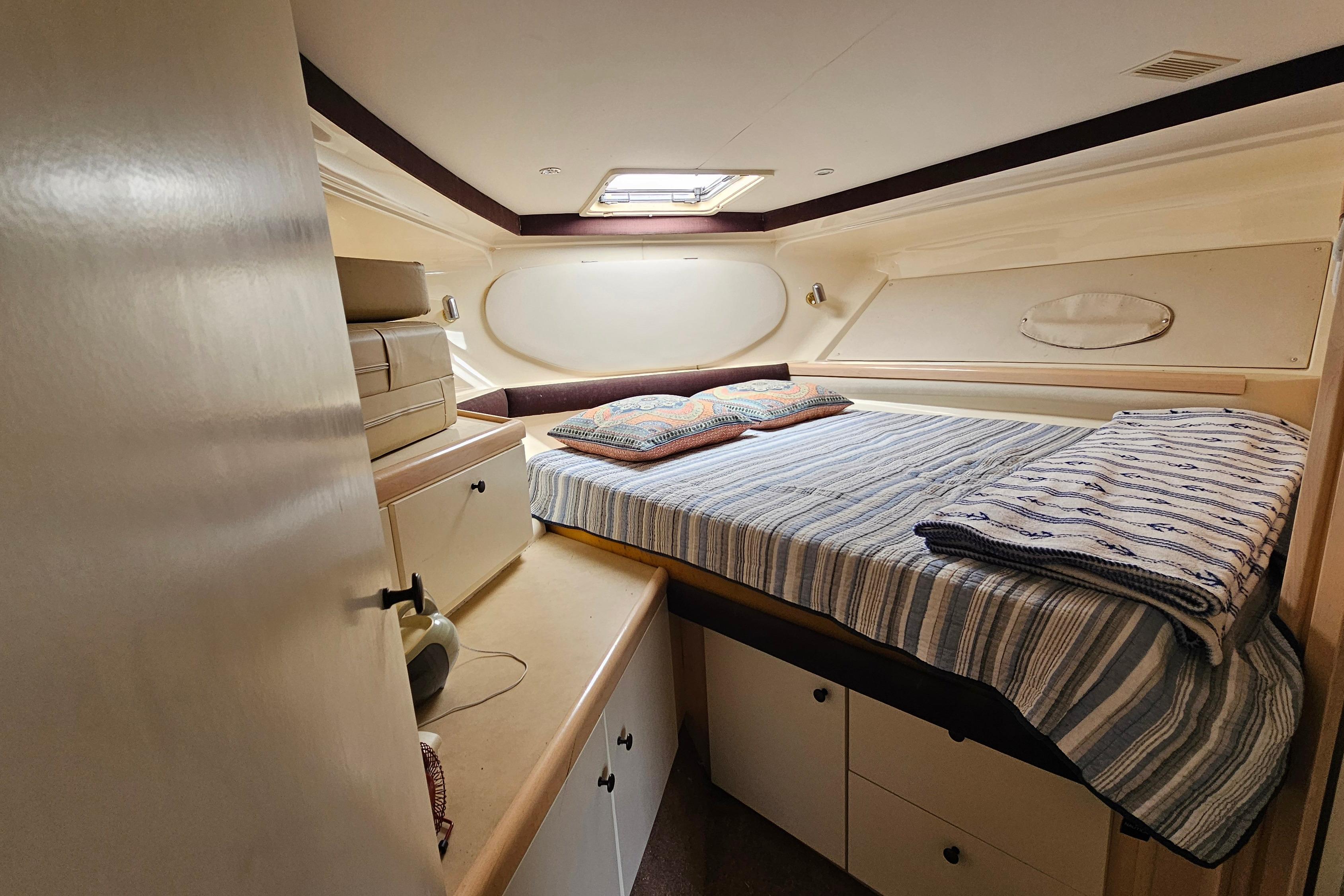 Cozy cabin interior of 1999 Carver 350 Mariner yacht with bed and storage.