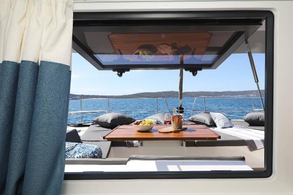 Bali 4.8 yacht interior view with ocean backdrop, featuring a dining setup, 2021 model.