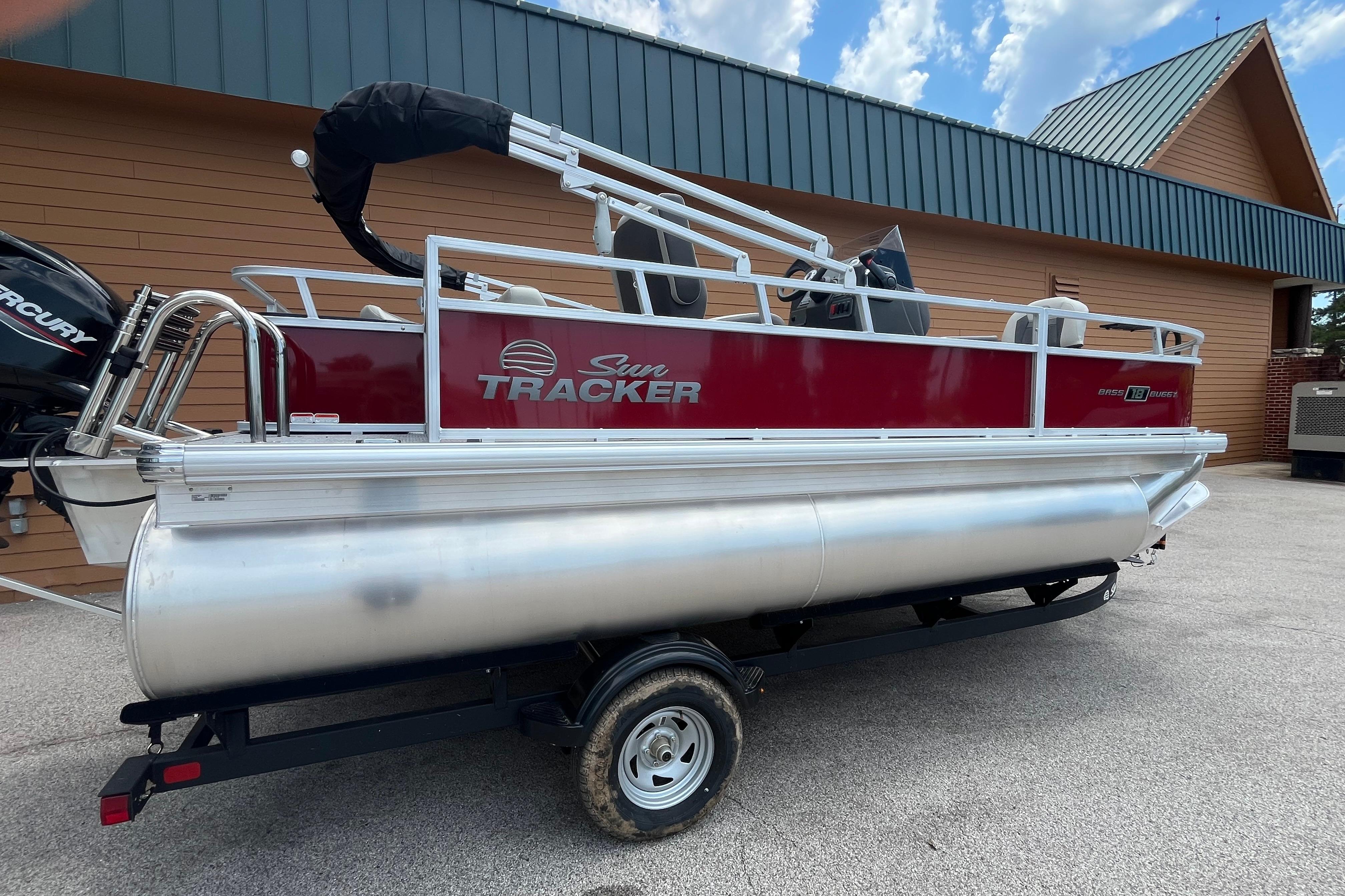 2026 Sun Tracker Bass Buggy 18 DLX pontoon boat on trailer, parked outdoors.