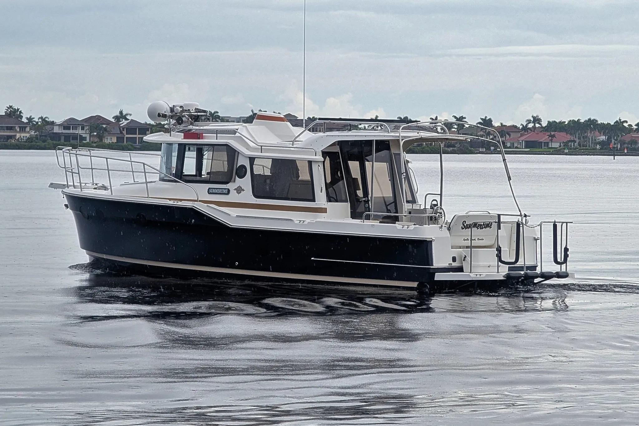 2015 Ranger Tugs R-29 S boat cruising on calm waters near residential area.