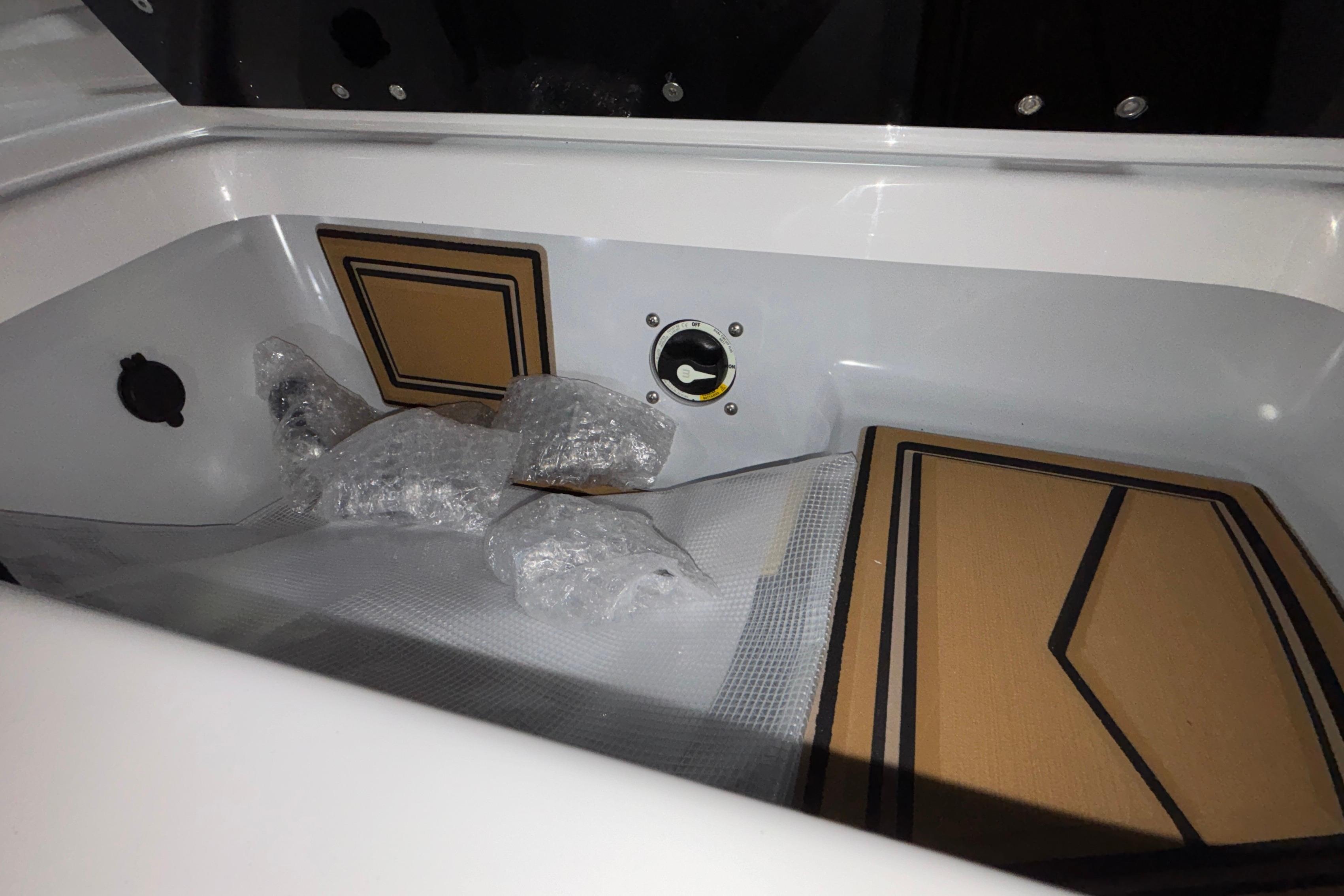 Interior storage compartment of 2026 Tigé 22RZX boat with bubble wrap and padding.
