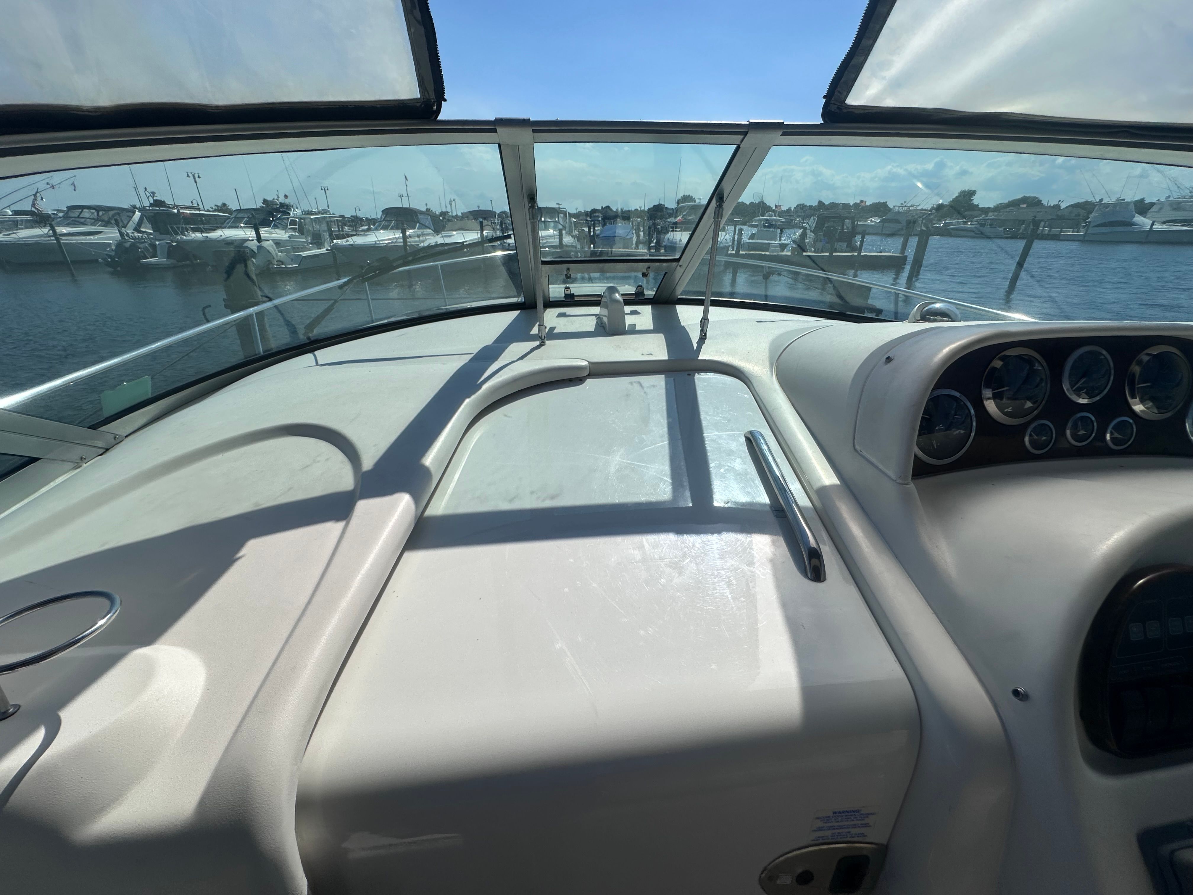 The image shows the cockpit of a 2002 Sea Ray 300 Sundancer with a view of the marina.