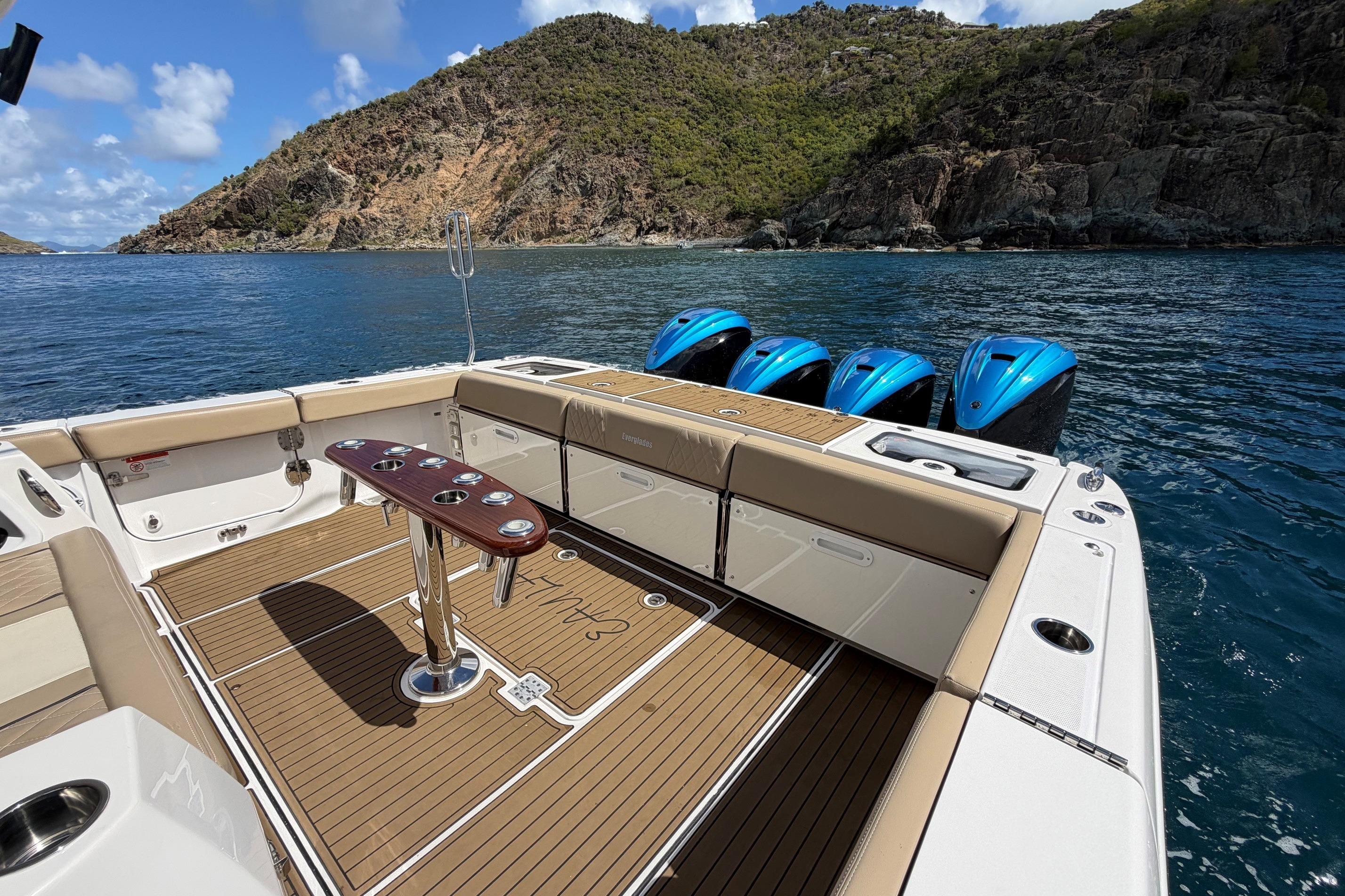 2022 Everglades 455 Center Console boat with four engines, docked near rocky coastline.