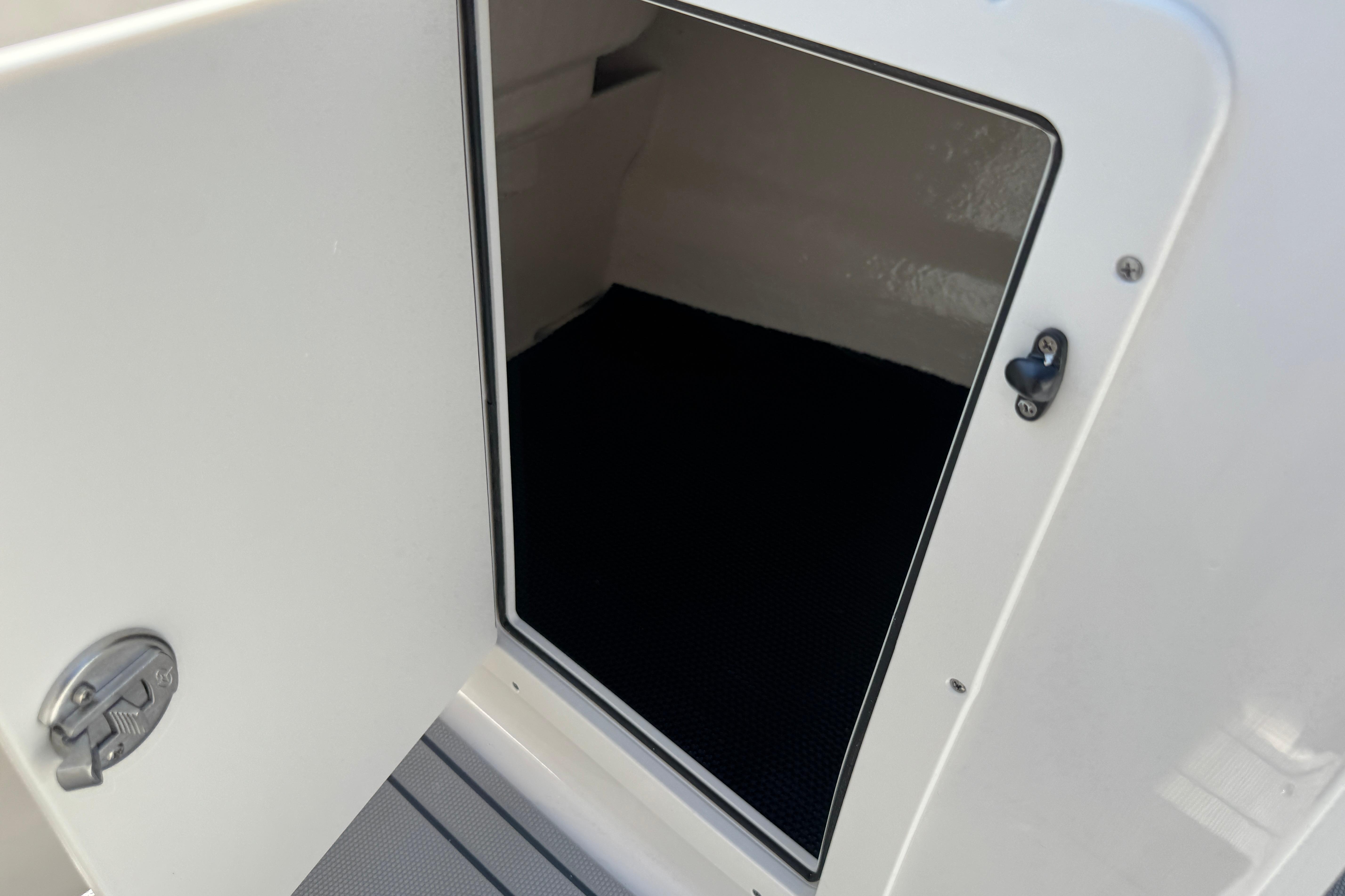 Open storage compartment on 2026 Chaparral 21 SSi boat, showcasing interior space.