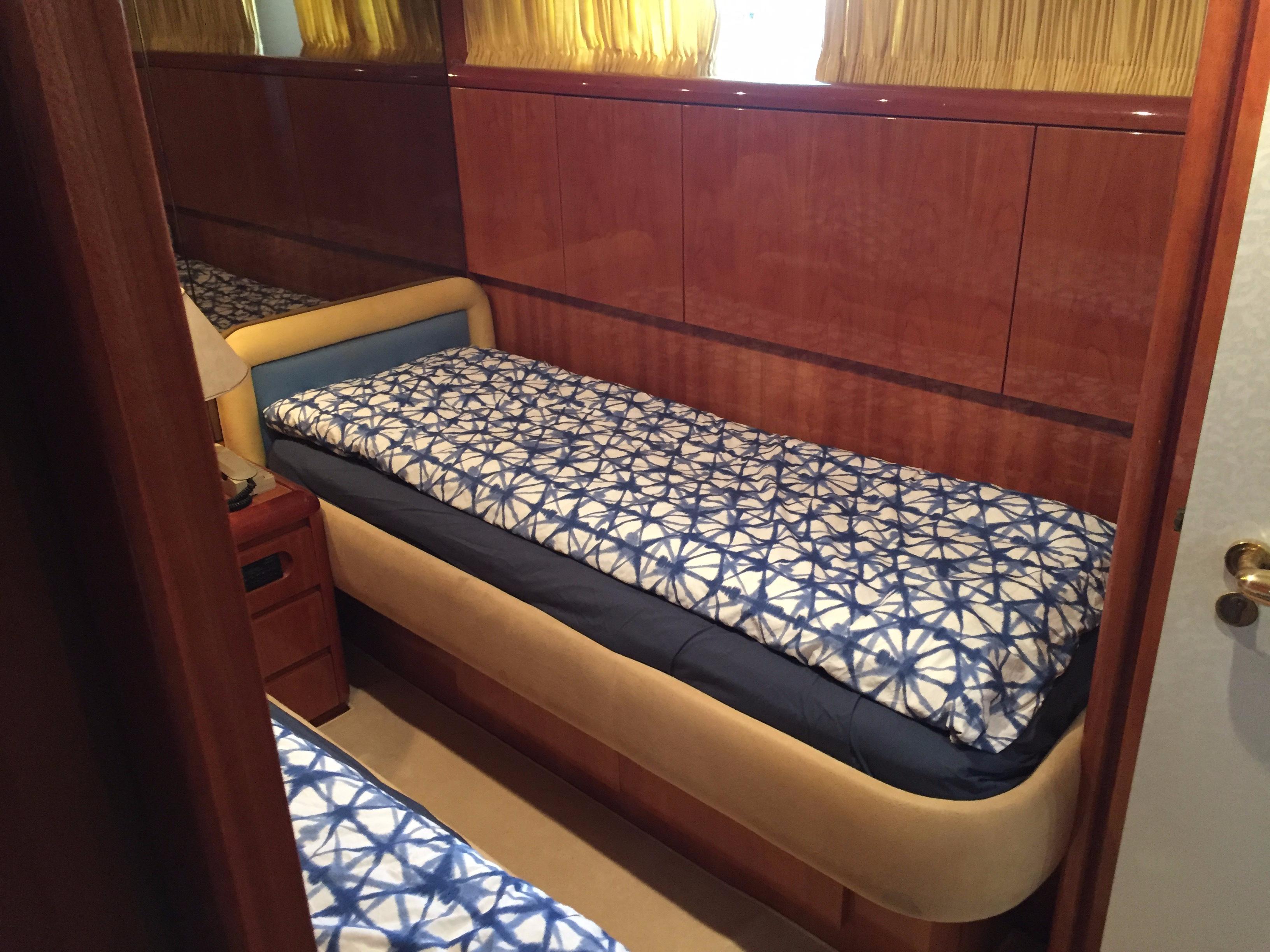 Cozy cabin interior of 1994 Falcon 76 yacht with patterned bedding and wooden paneling.