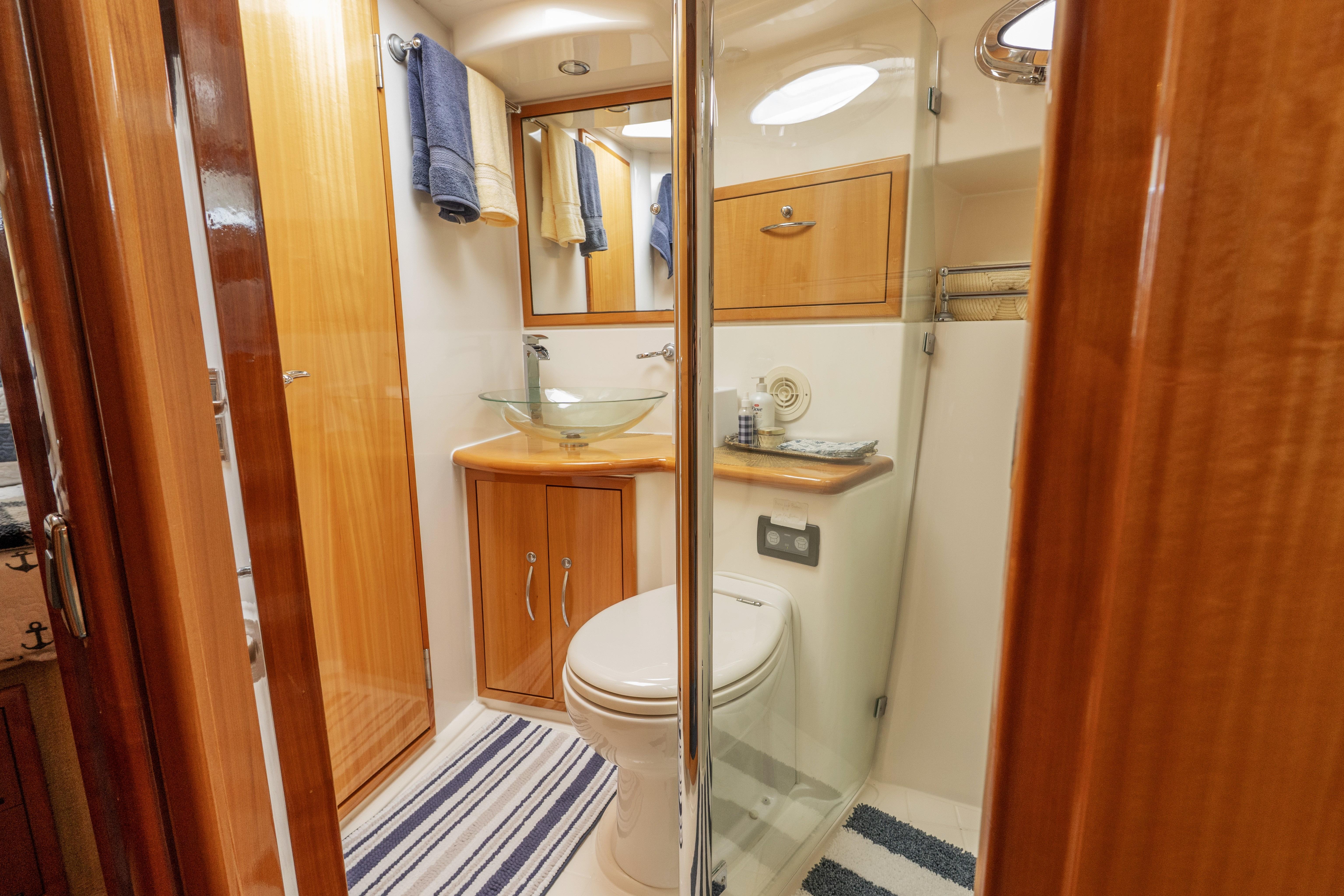 Luxurious bathroom in 2008 Maritimo 52 yacht with glass sink and wooden cabinetry.