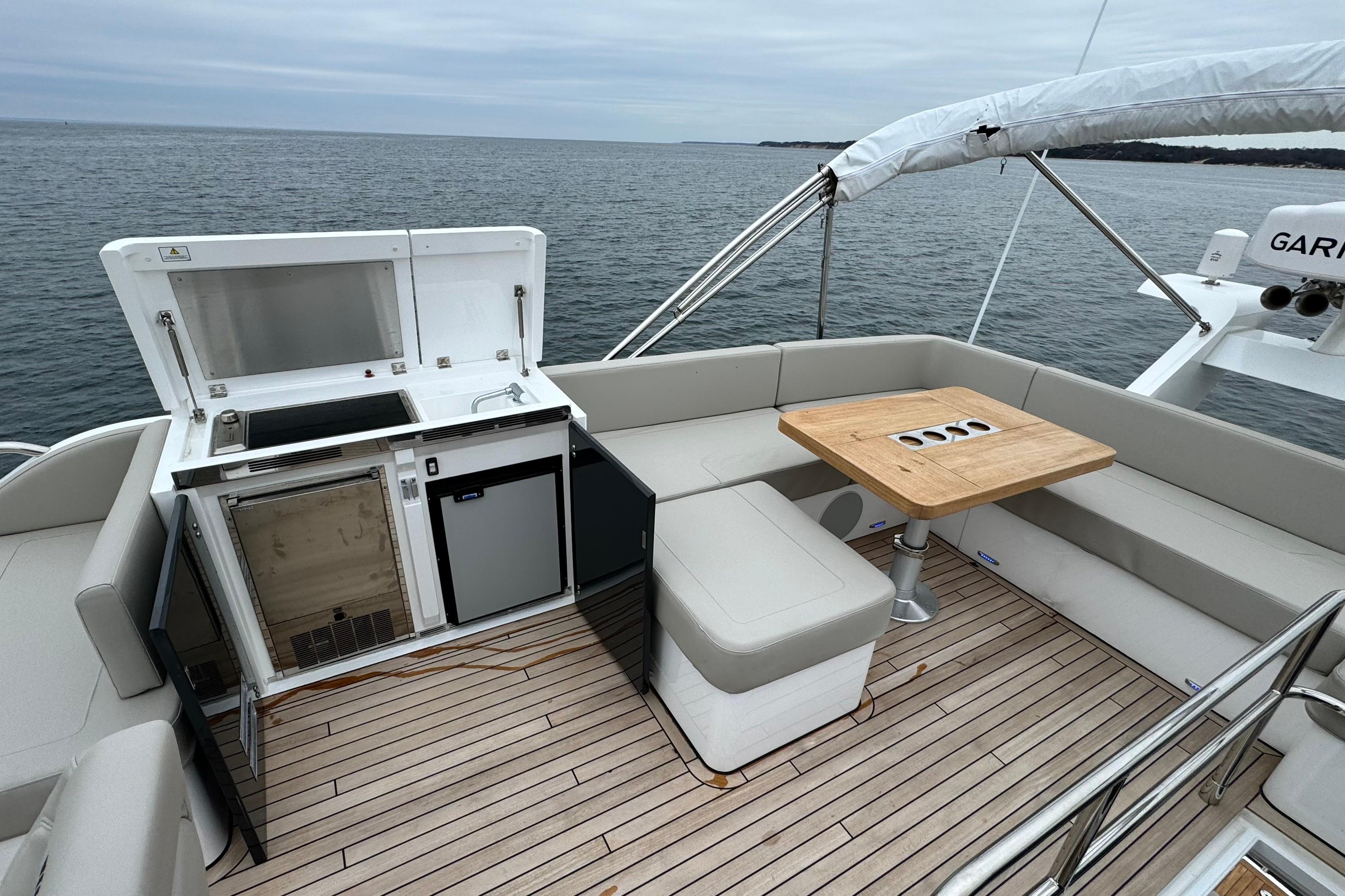 2024 Fairline Squadron 50 yacht deck with seating, table, and kitchenette overlooking the ocean.