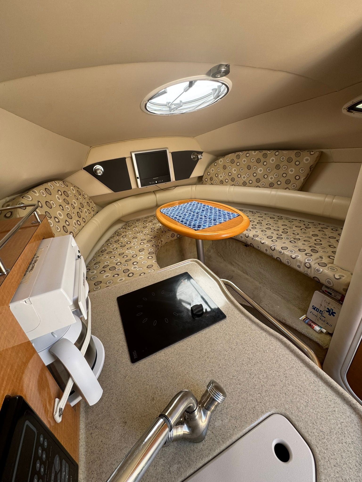 Interior of a yacht with seating area, table, and kitchenette.